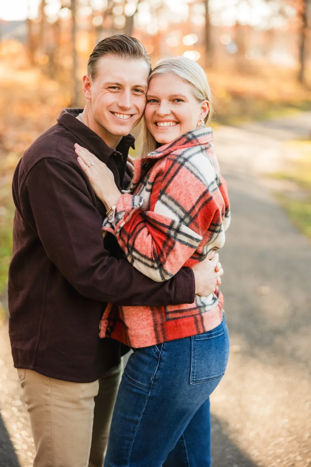 Maddy and Tyler hug and laugh toward the camera on a tree-lined path at Grand View Lodge