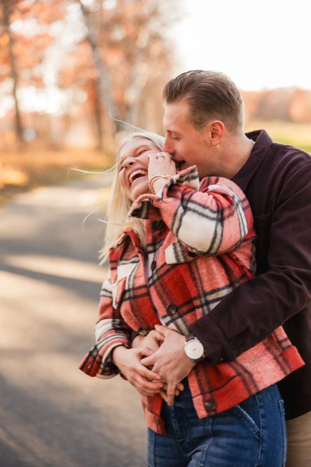 Tyler wraps his arms around Maddy from behind as she laughs, her hair lit by the low sun — Tim Larsen Photography, Brainerd Lakes MN
