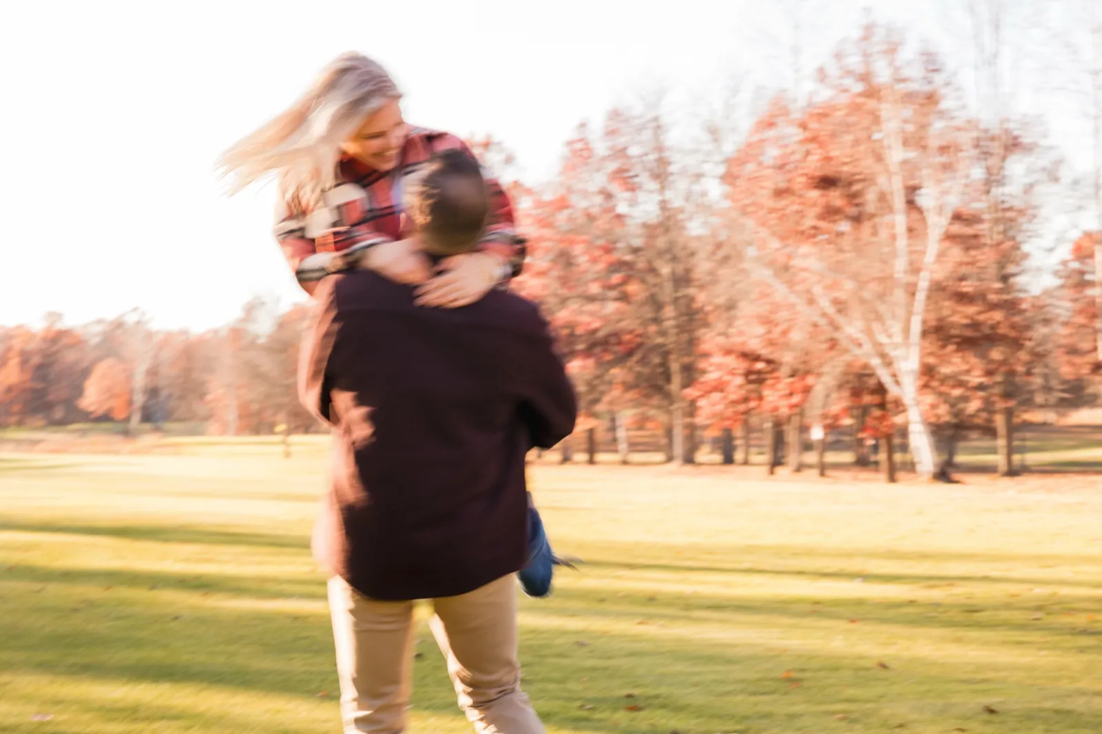 Tyler lifts and spins Maddy across the grass, both figures blurred with motion against orange trees — Tim Larsen Photography, Brainerd Lakes MN