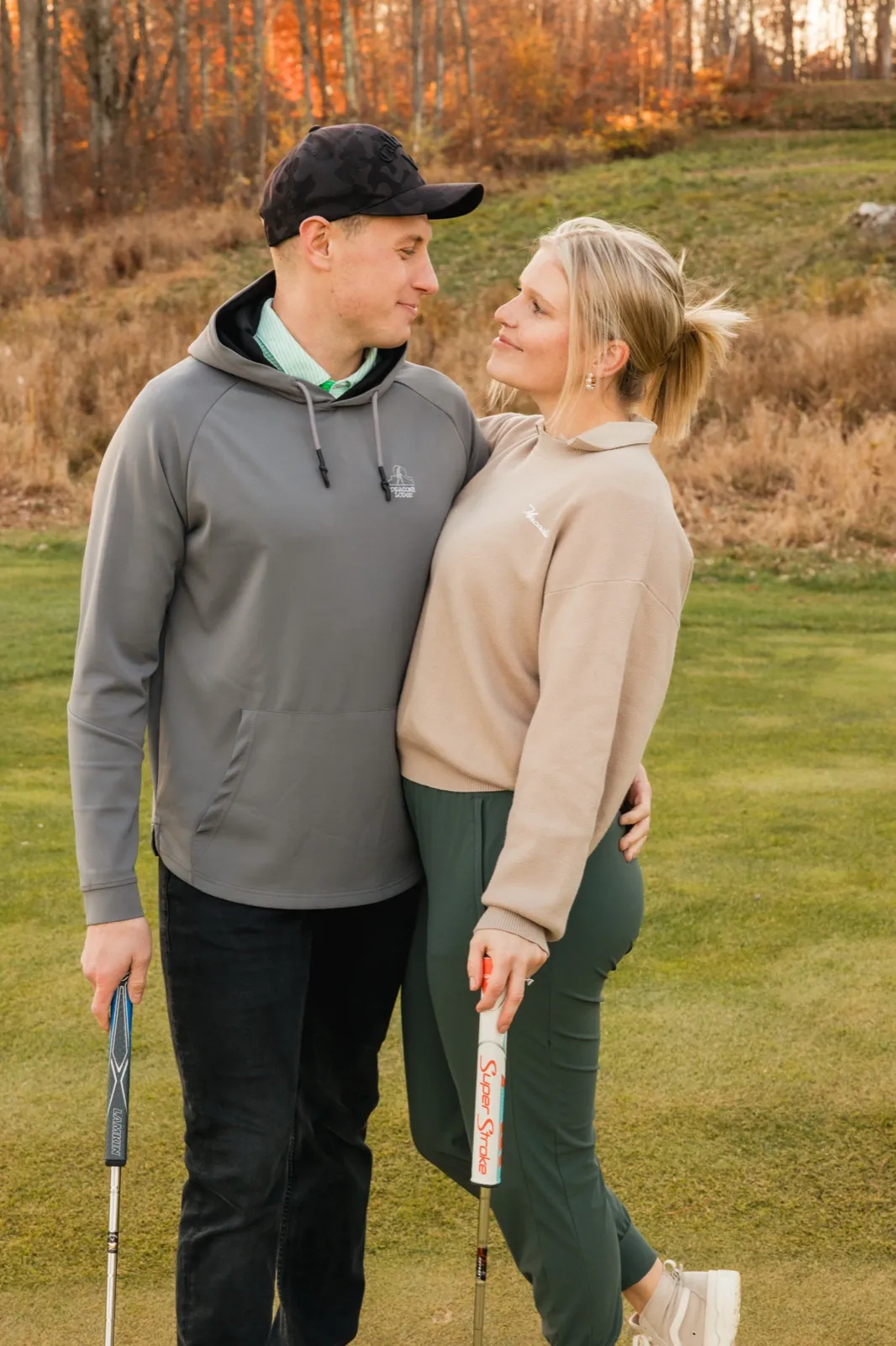 Maddy looks up at Tyler as they stand close on the green holding putters — Tim Larsen Photography, Brainerd Lakes MN