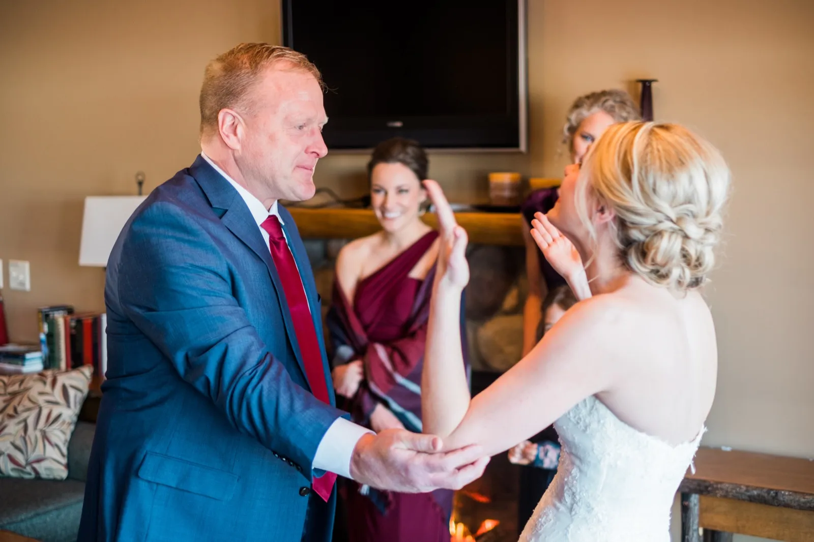 Morgan’s father in a blue suit and red tie reaches for her hands as he sees her in her wedding dress.