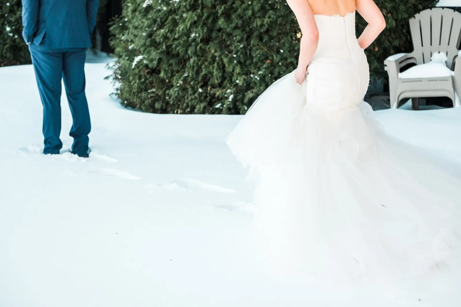 Morgan holds her tulle train above the snow as she approaches Cole, who waits with his back turned.
