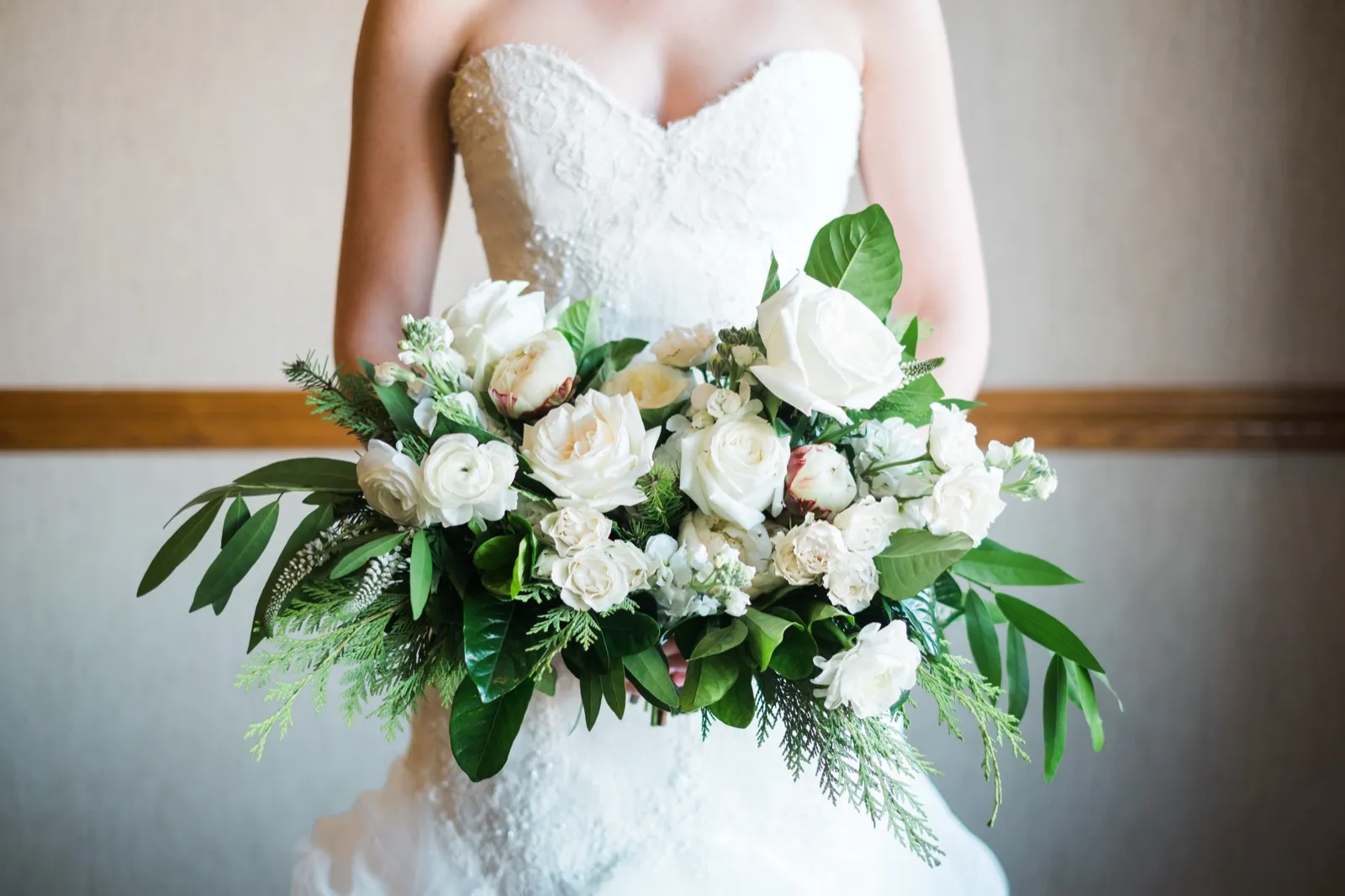 A close view of Morgan’s strapless lace bodice and white bouquet with trailing greenery.