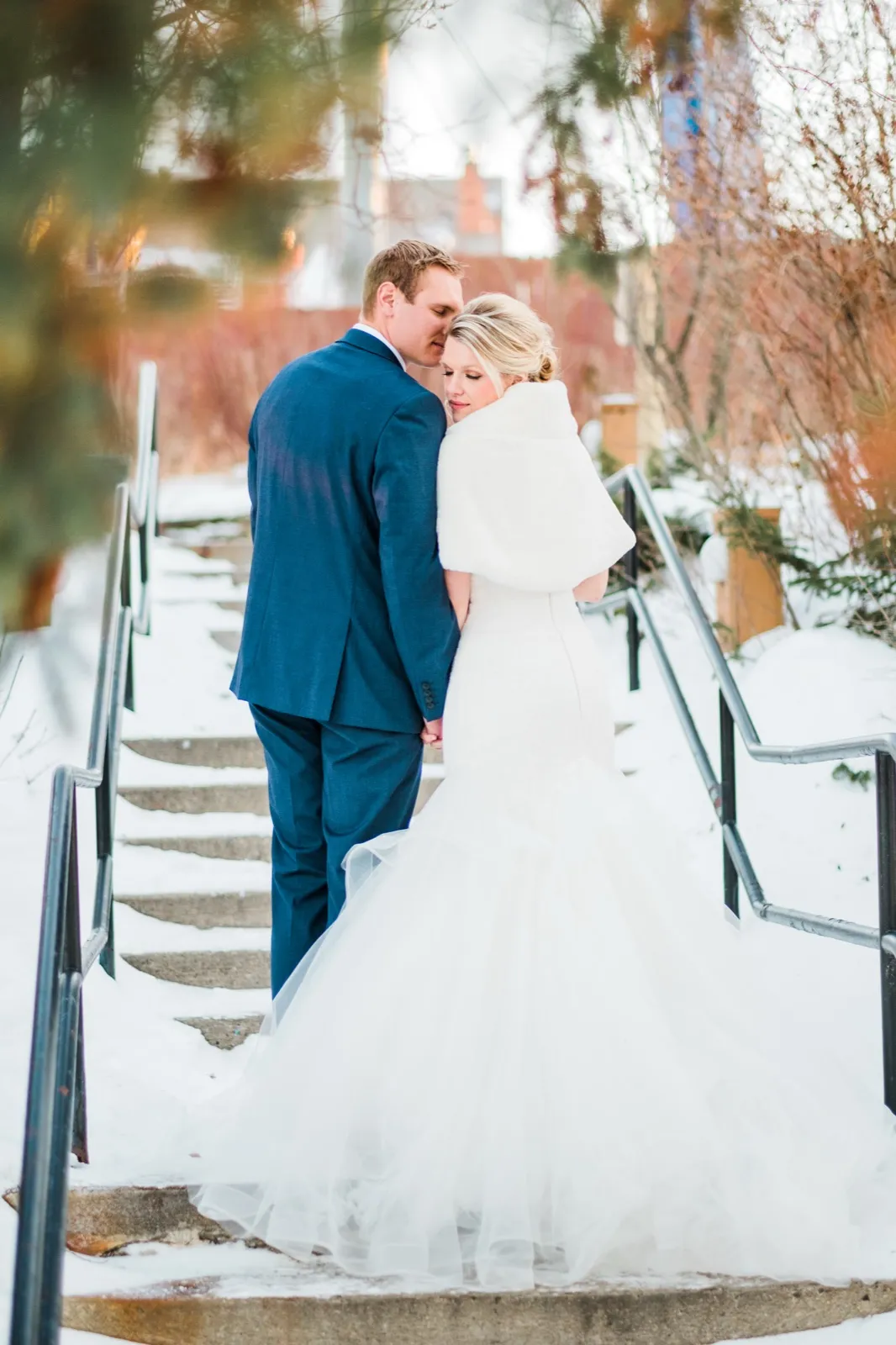 Morgan and Cole look back toward the camera from snowy stairs framed by winter branches.