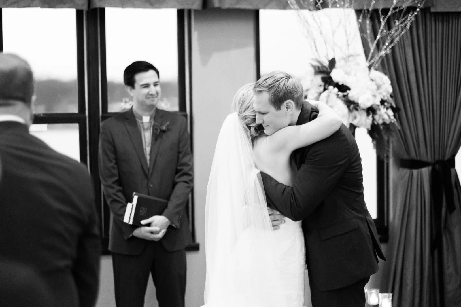 Morgan and Cole embrace during the ceremony while their officiant smiles beside them.