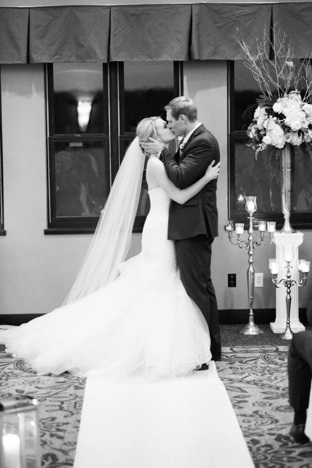 Morgan and Cole kiss during their ceremony beside a tall candelabra, with her long veil trailing across the floor.
