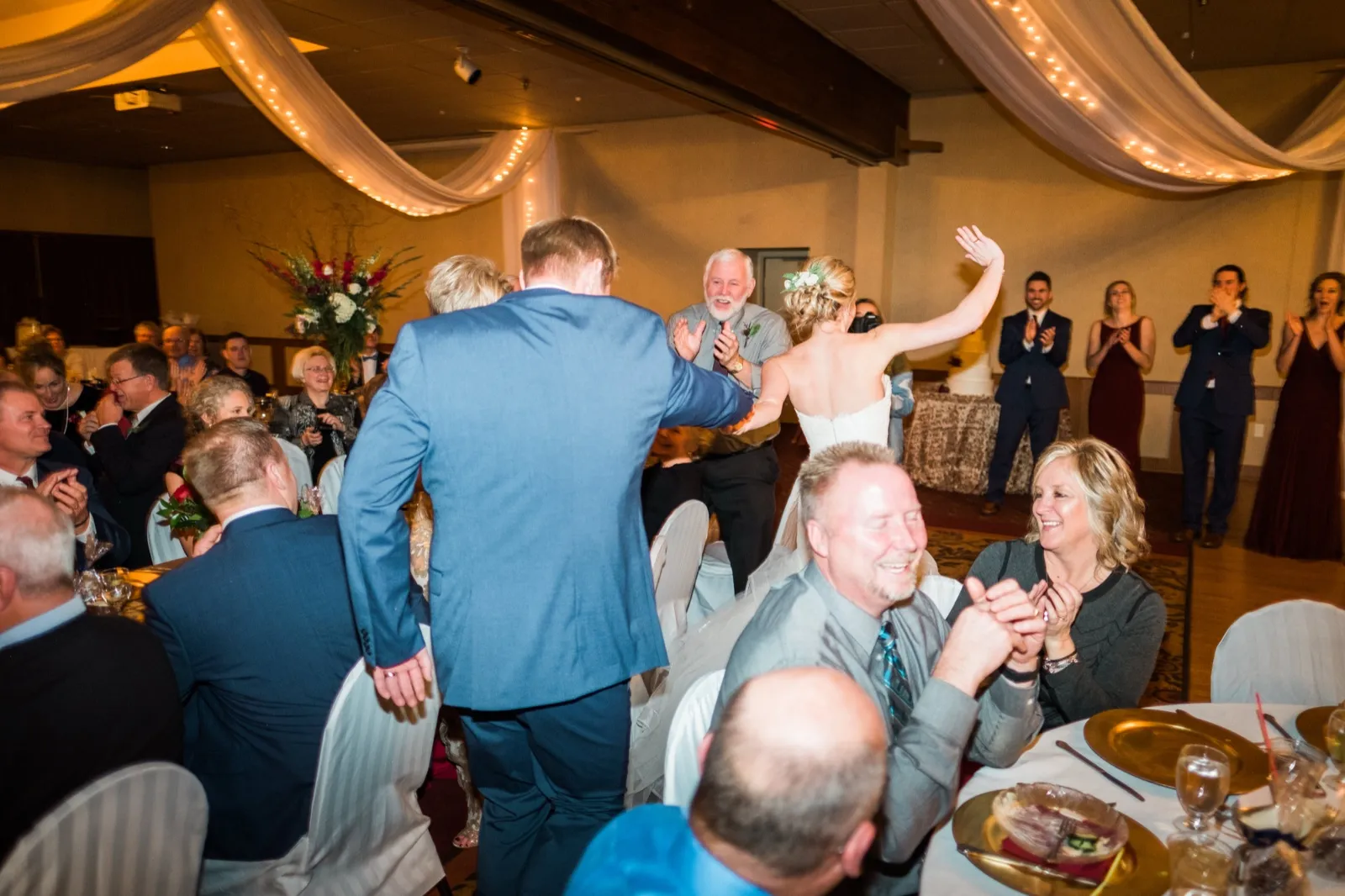 Morgan raises an arm as she and Cole enter their reception to applause beneath draped fabric and string lights.