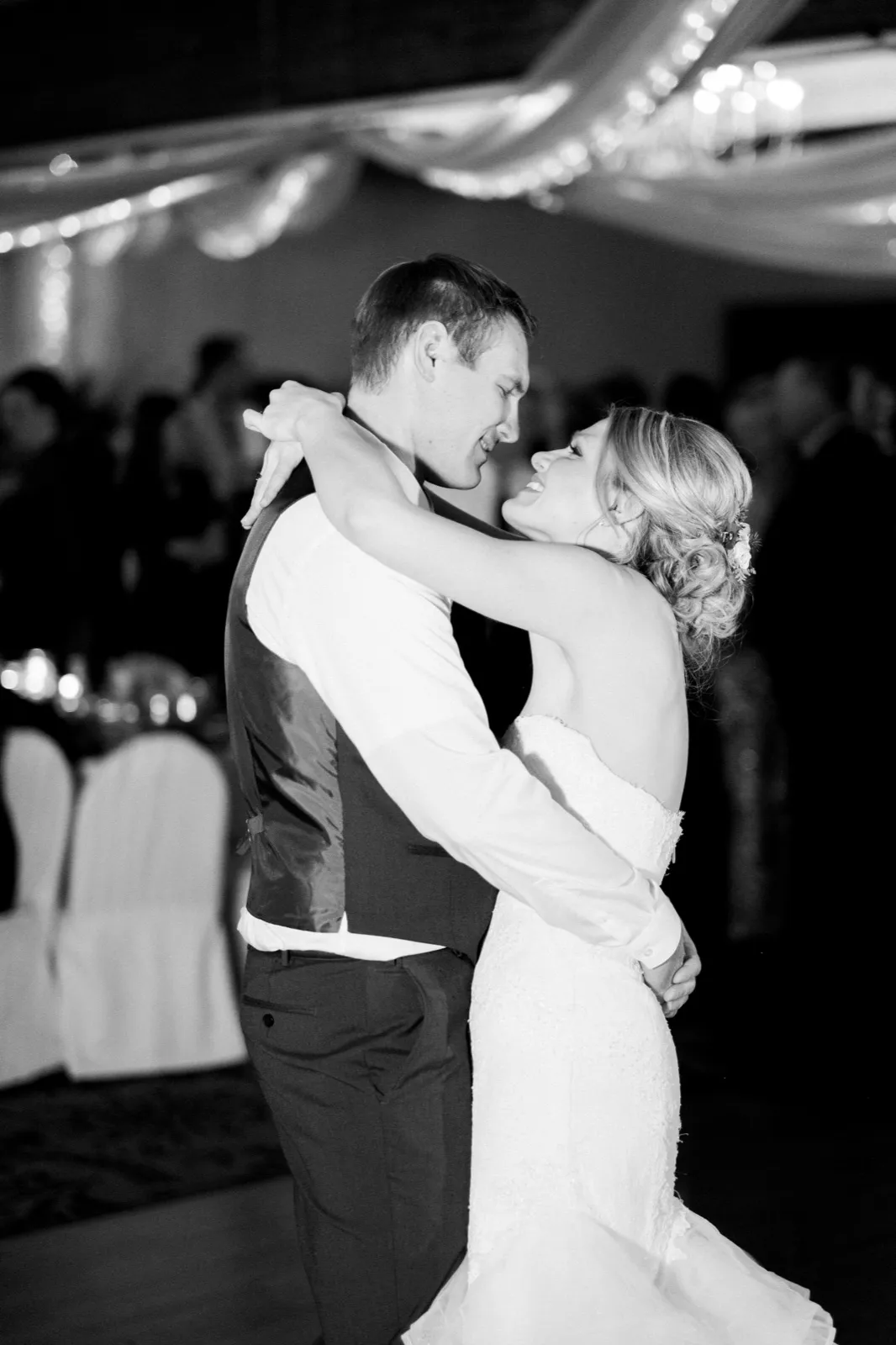 Morgan looks up at Cole with her arms around his neck during their first dance, photographed in black and white