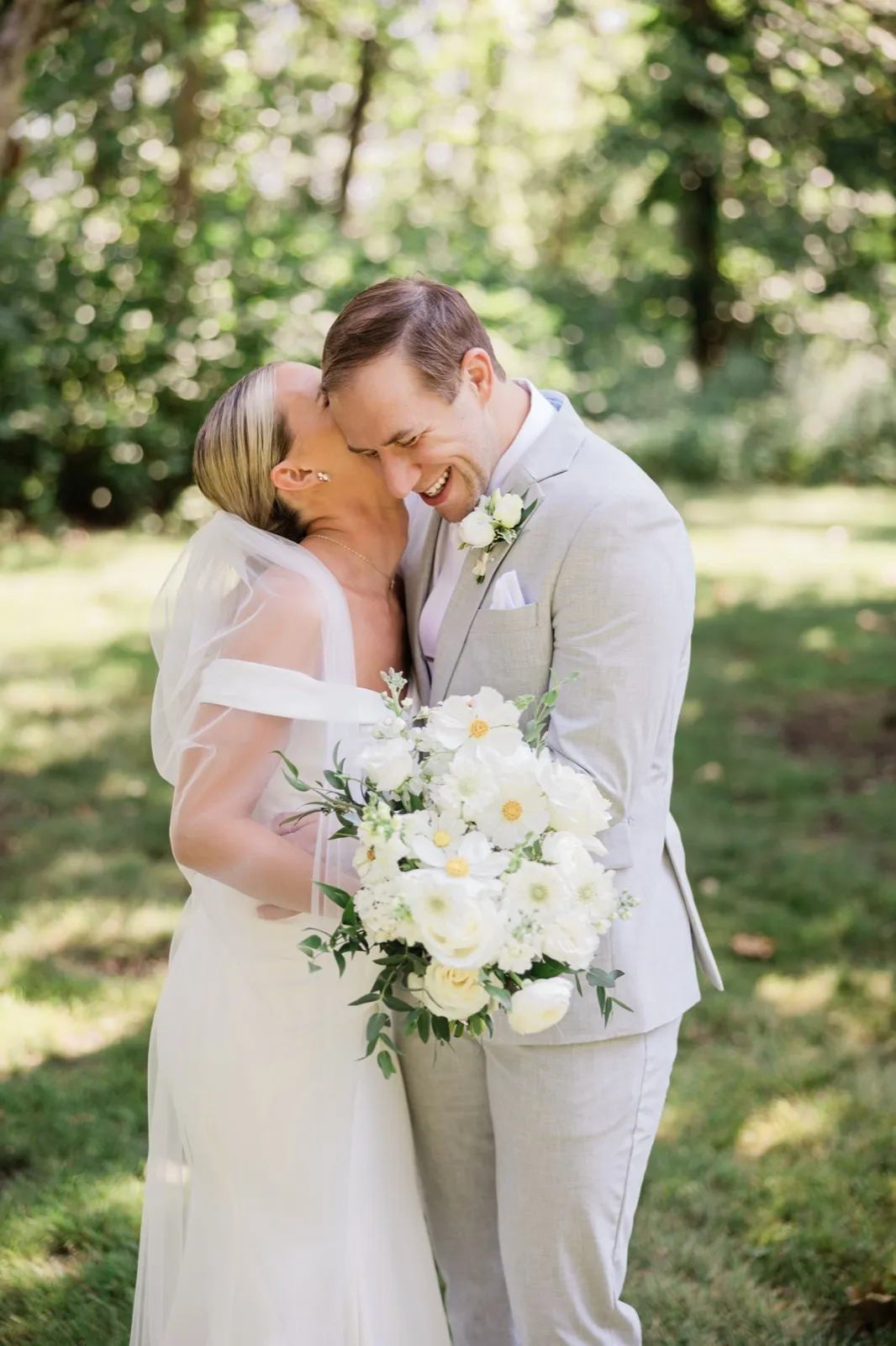 Josse and Alex hold each other close on a shaded lawn under the oaks, her veil trailing behind her — Tim Larsen Photography, Brainerd Lakes MN