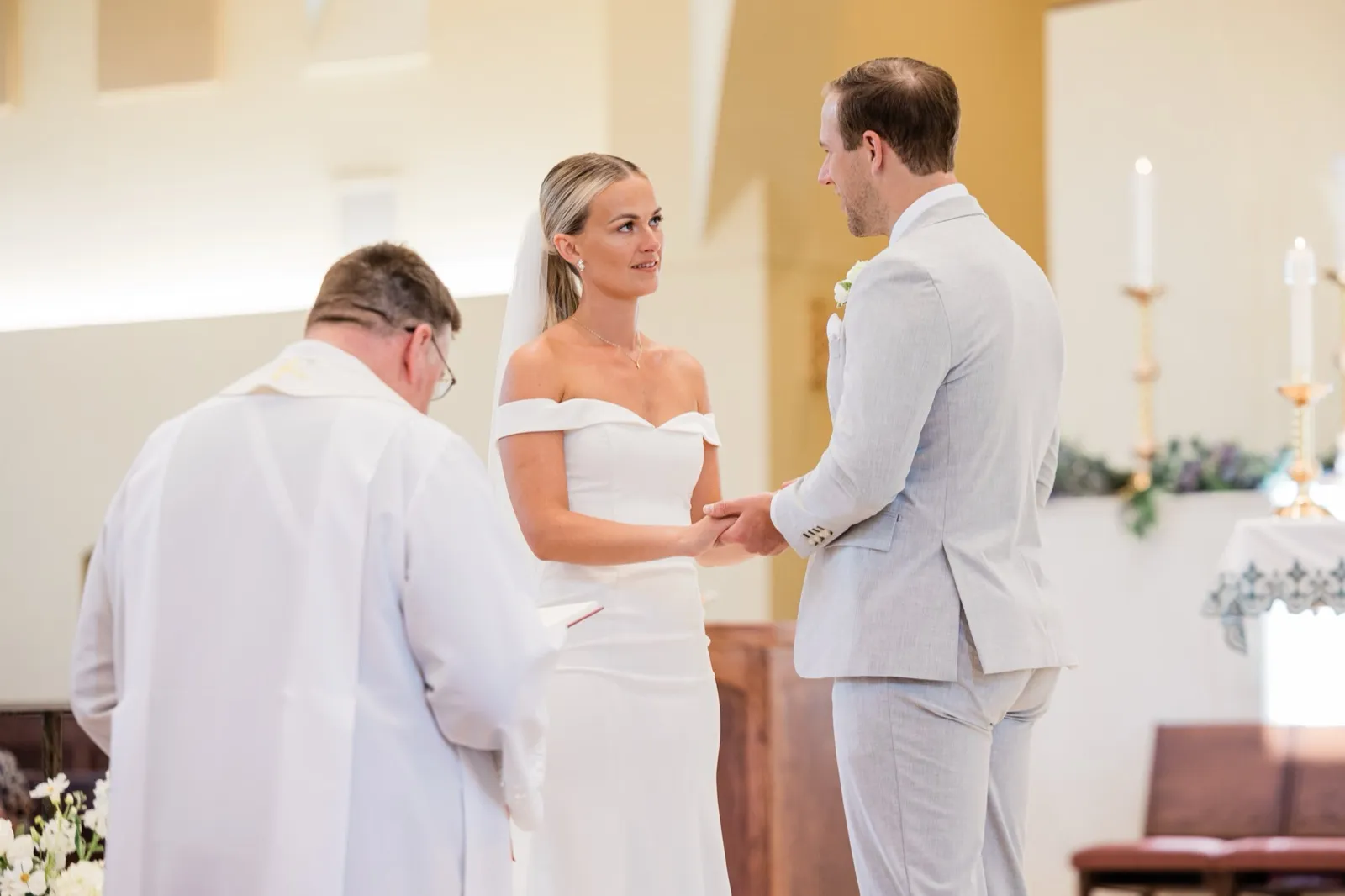 Josse holds Alex's hands and looks up at him during their vows at the altar — Tim Larsen Photography, Brainerd Lakes MN