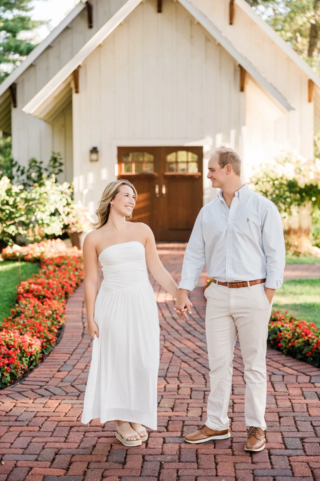 Olivia and Adam hold hands and smile at each other in front of the white chapel at Grand View Lodge — Tim Larsen Photography
