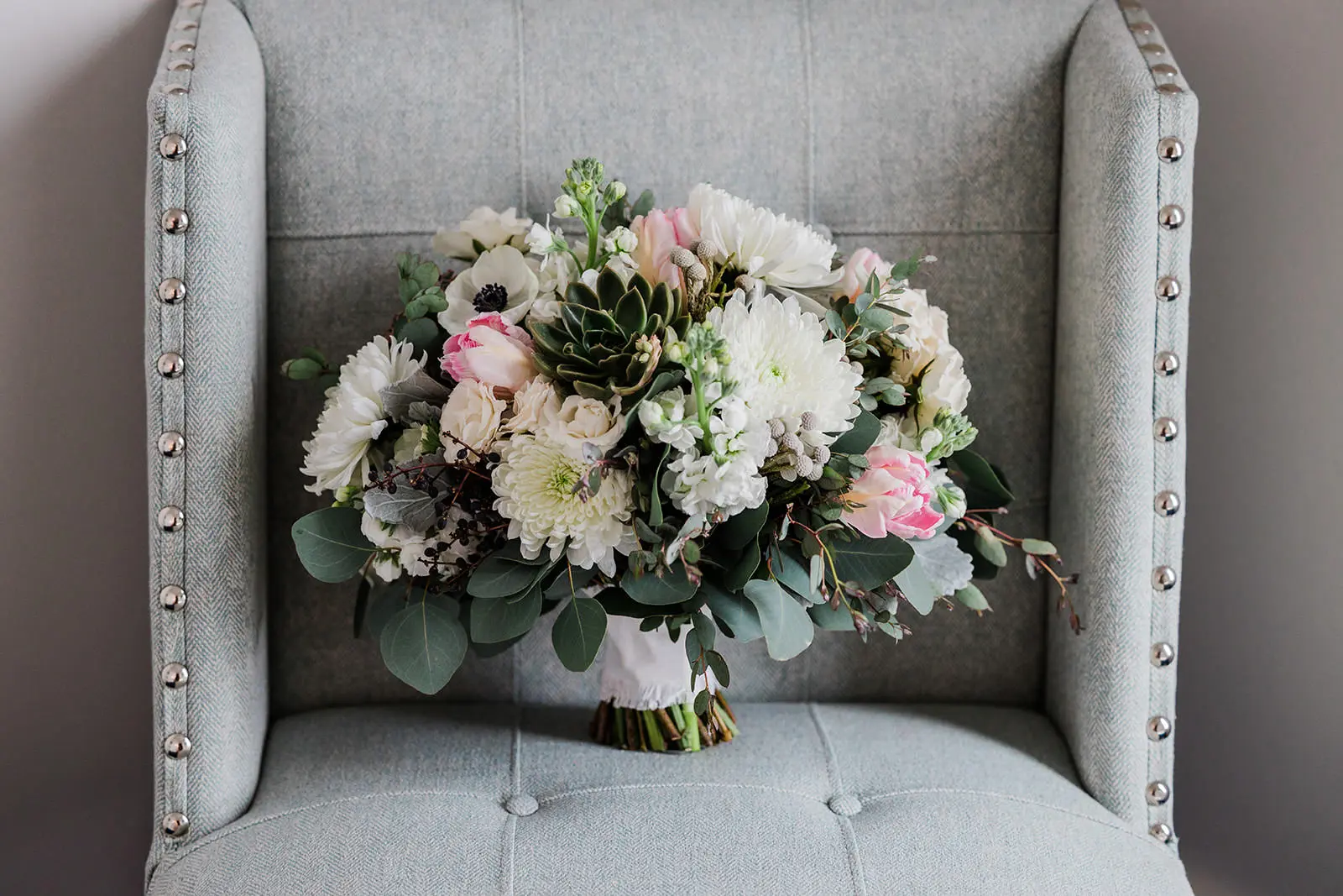 Bouquet on gray chair — white dahlias, anemones, succulents, and eucalyptus — Tim Larsen Photography, Brainerd Lakes MN