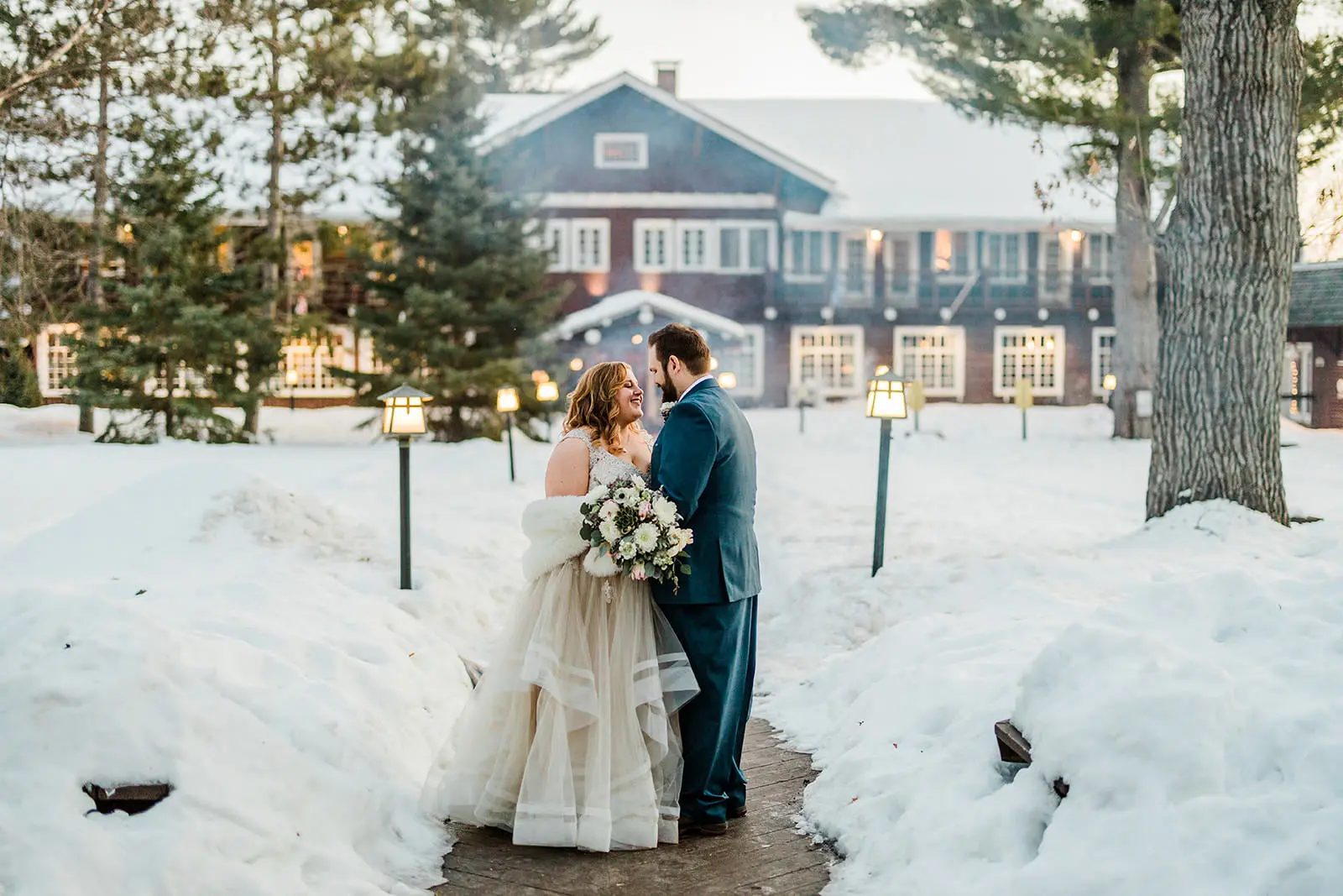 Couple on the snowy path in front of the Historic Main Lodge — evening light at Grand View Lodge — Tim Larsen Photography, Brainerd Lakes MN