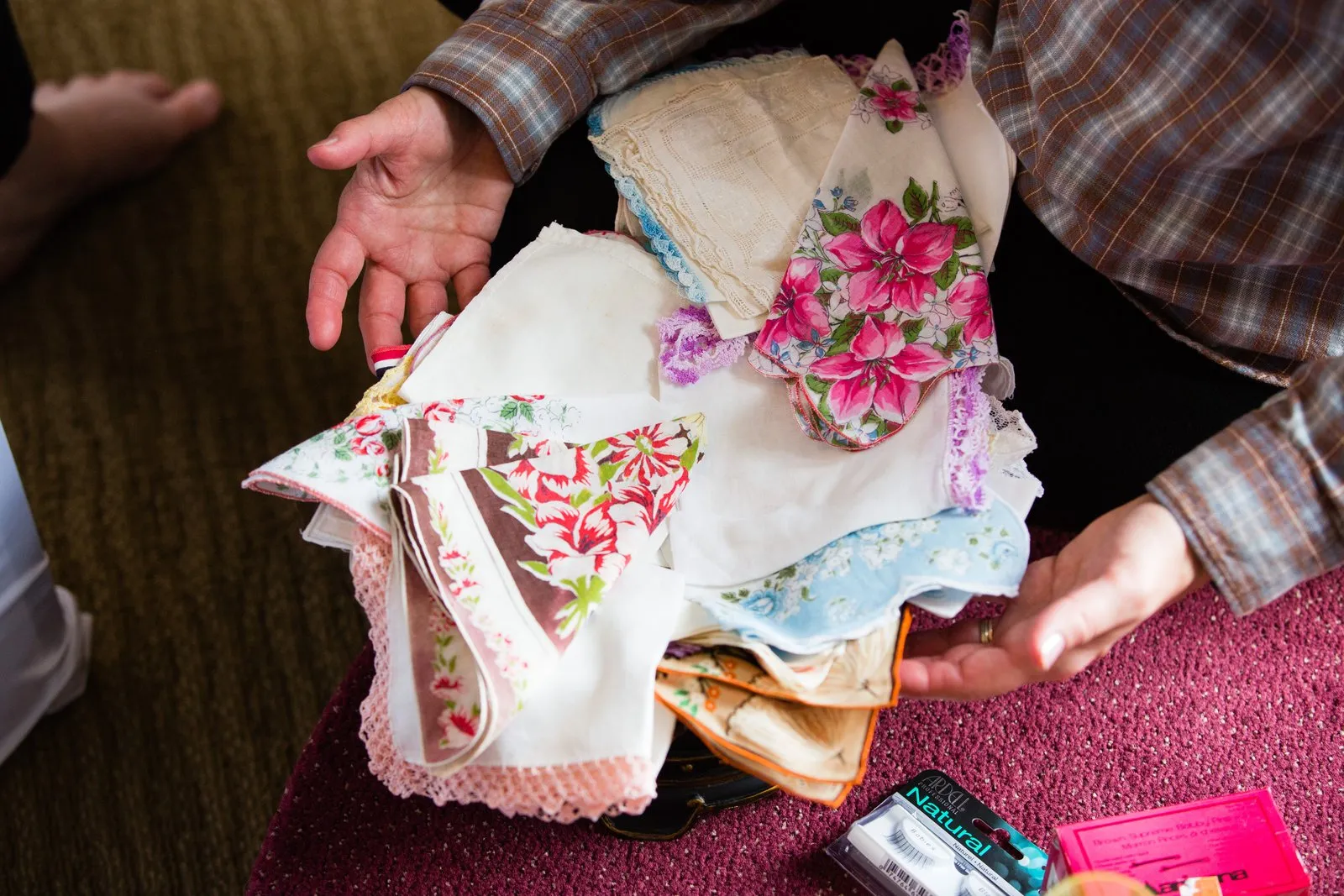 Overhead view of hands holding vintage floral handkerchiefs on a lap — bridal getting-ready detail at the Greysolon — Tim Larsen Photography, Duluth MN