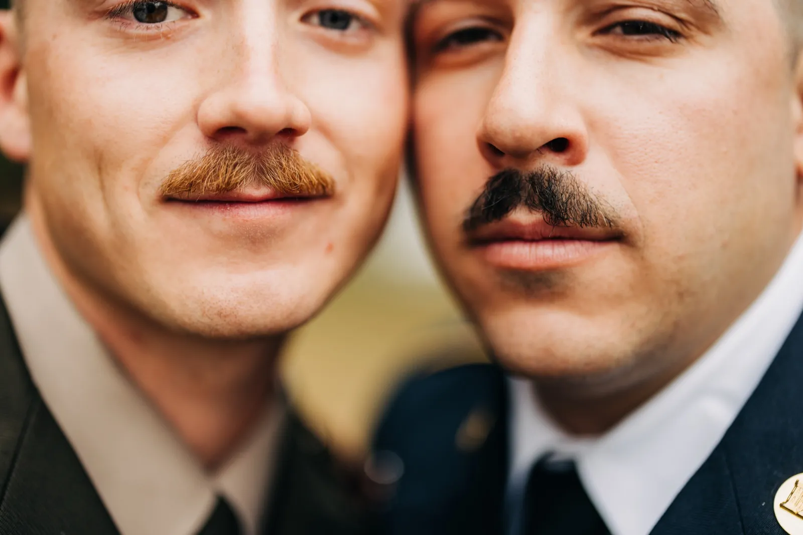 An extreme close-up of two grooms pressed cheek-to-cheek, framing their mustaches, lips, and eyes in tight detail. — Tim Larsen Photography, Brainerd Lakes MN