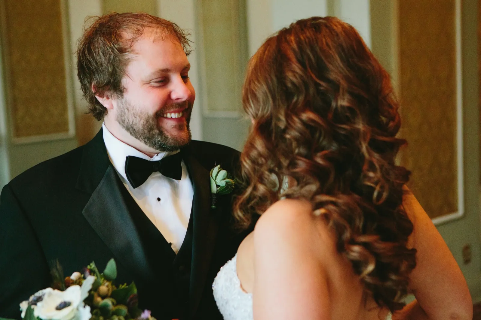 First look — the groom's joyful reaction over the bride's curled hair in the foreground, boutonniere visible — Greysolon Plaza — Tim Larsen Photography, Duluth MN