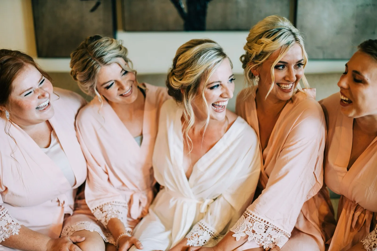 Shannon laughs as her four bridesmaids in blush robes lean in around her on the wedding morning at Madden's on Gull Lake — Tim Larsen Photography, Brainerd Lakes MN