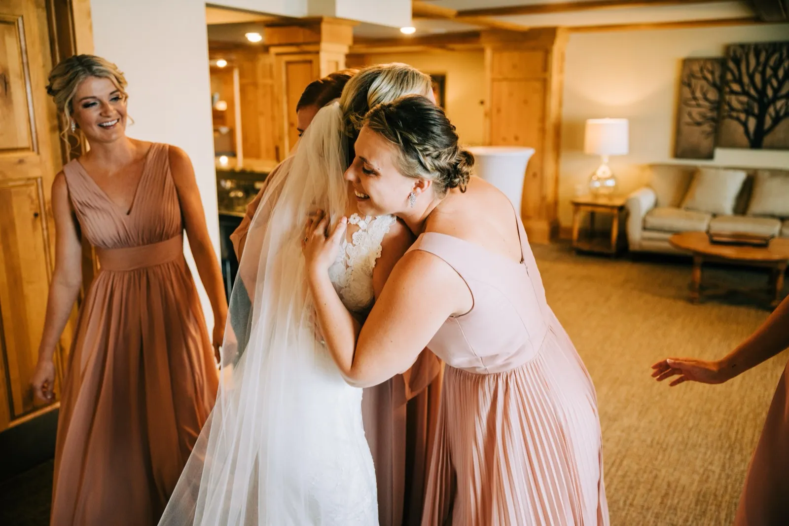 Shannon hugs a bridesmaid in blush as another laughs nearby in the getting-ready suite — Tim Larsen Photography, Brainerd Lakes MN