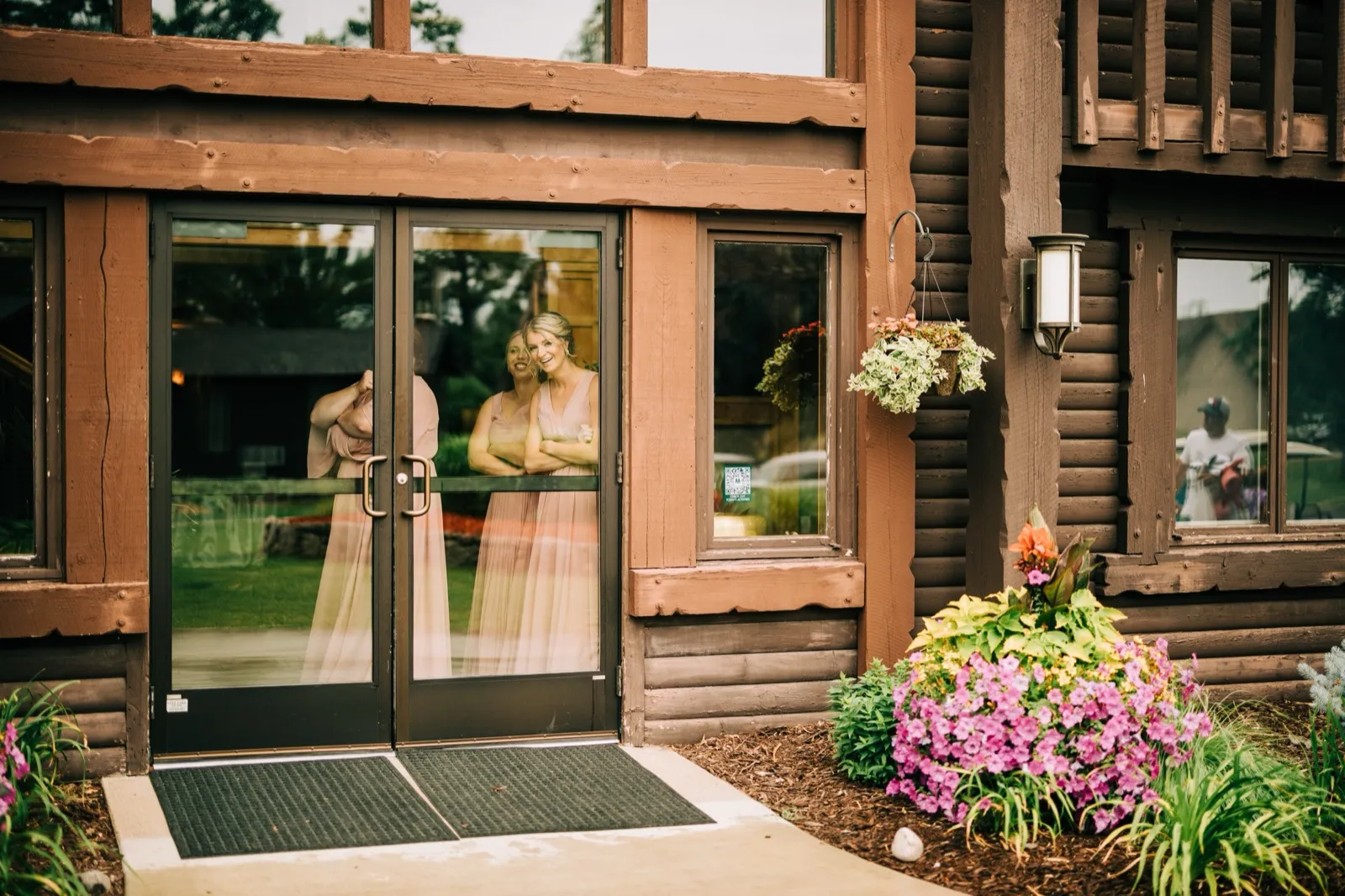 Shannon and two bridesmaids framed behind the glass doors of the log-sided lodge entrance at Madden's — Tim Larsen Photography, Brainerd Lakes MN