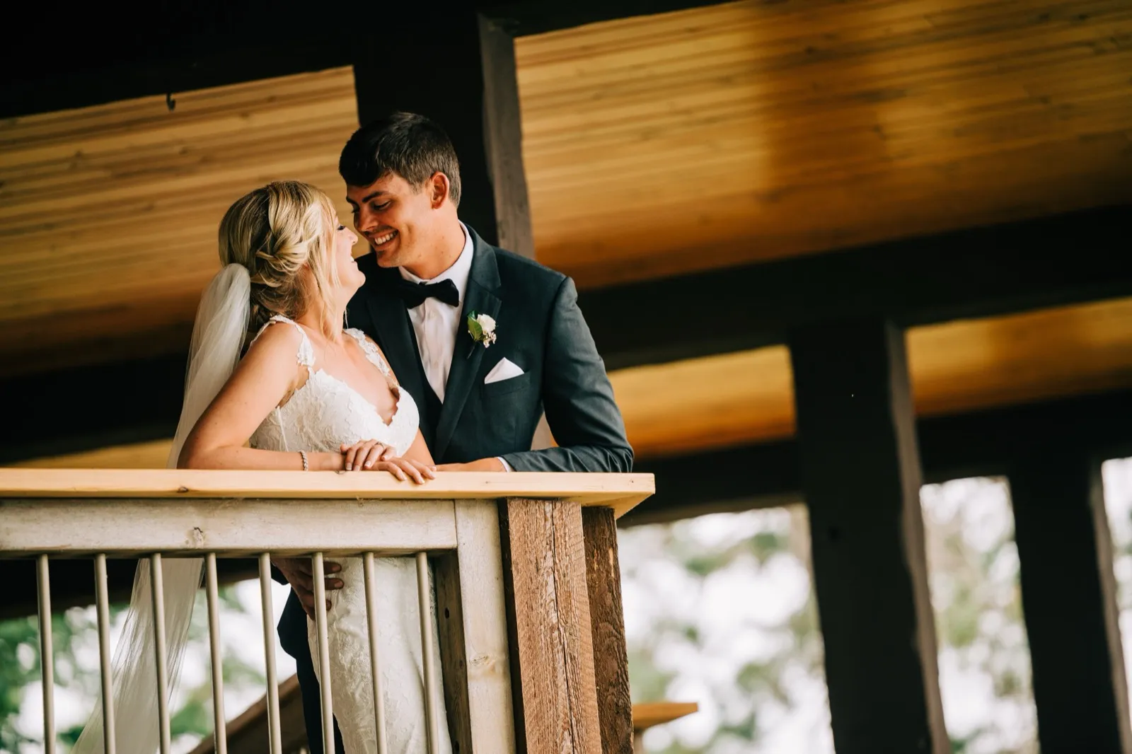 Shannon and Zach share a laugh on the covered porch, framed by warm timber beams at Madden's — Tim Larsen Photography, Brainerd Lakes MN