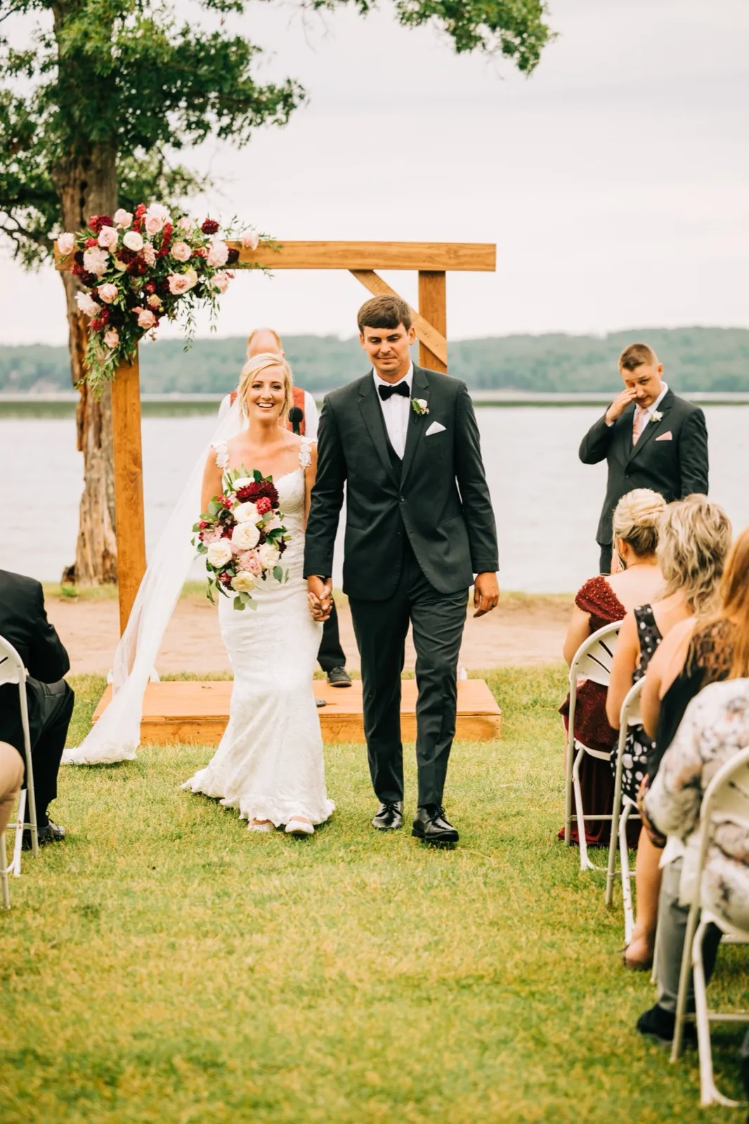 Shannon and Zach walk back down the aisle after their lakeside ceremony as a groomsman quietly wipes his eye at right — Tim Larsen Photography, Brainerd Lakes MN