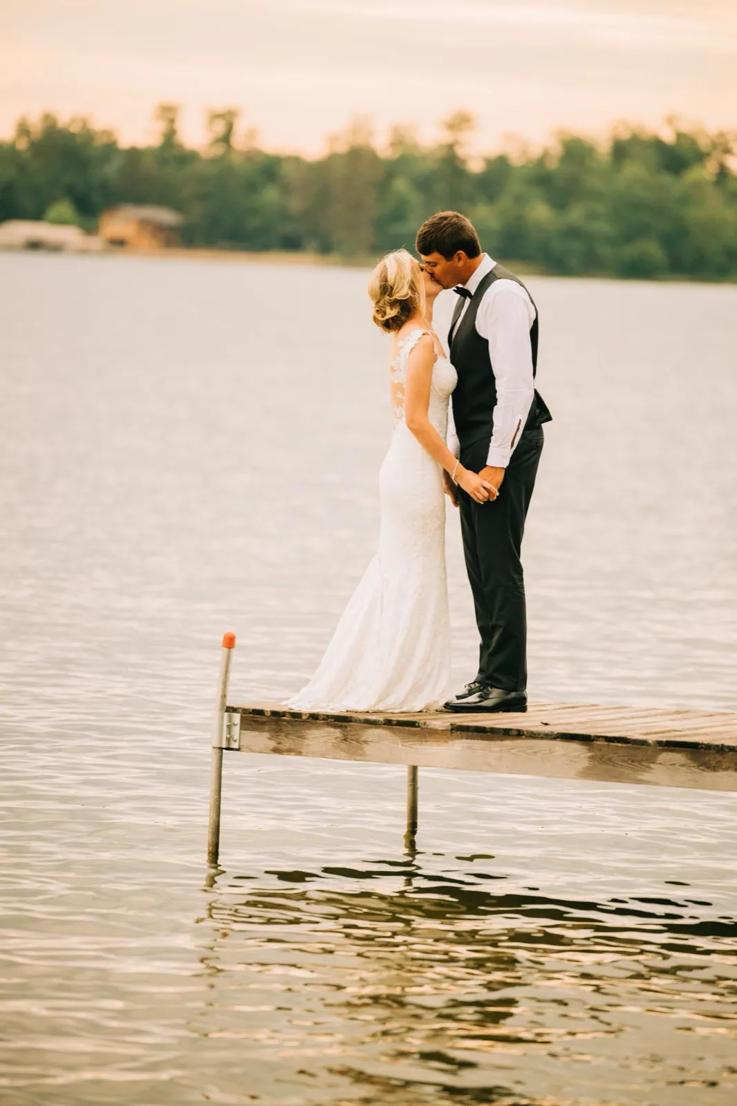 Shannon and Zach kiss at the end of a wooden dock as warm golden-hour light glows across Gull Lake — Tim Larsen Photography, Brainerd Lakes MN