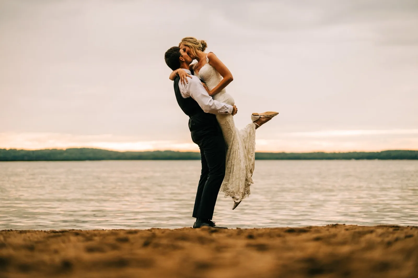 Zach lifts Shannon off the sandy lakeshore for a kiss as the last light fades over Gull Lake — Tim Larsen Photography, Brainerd Lakes MN