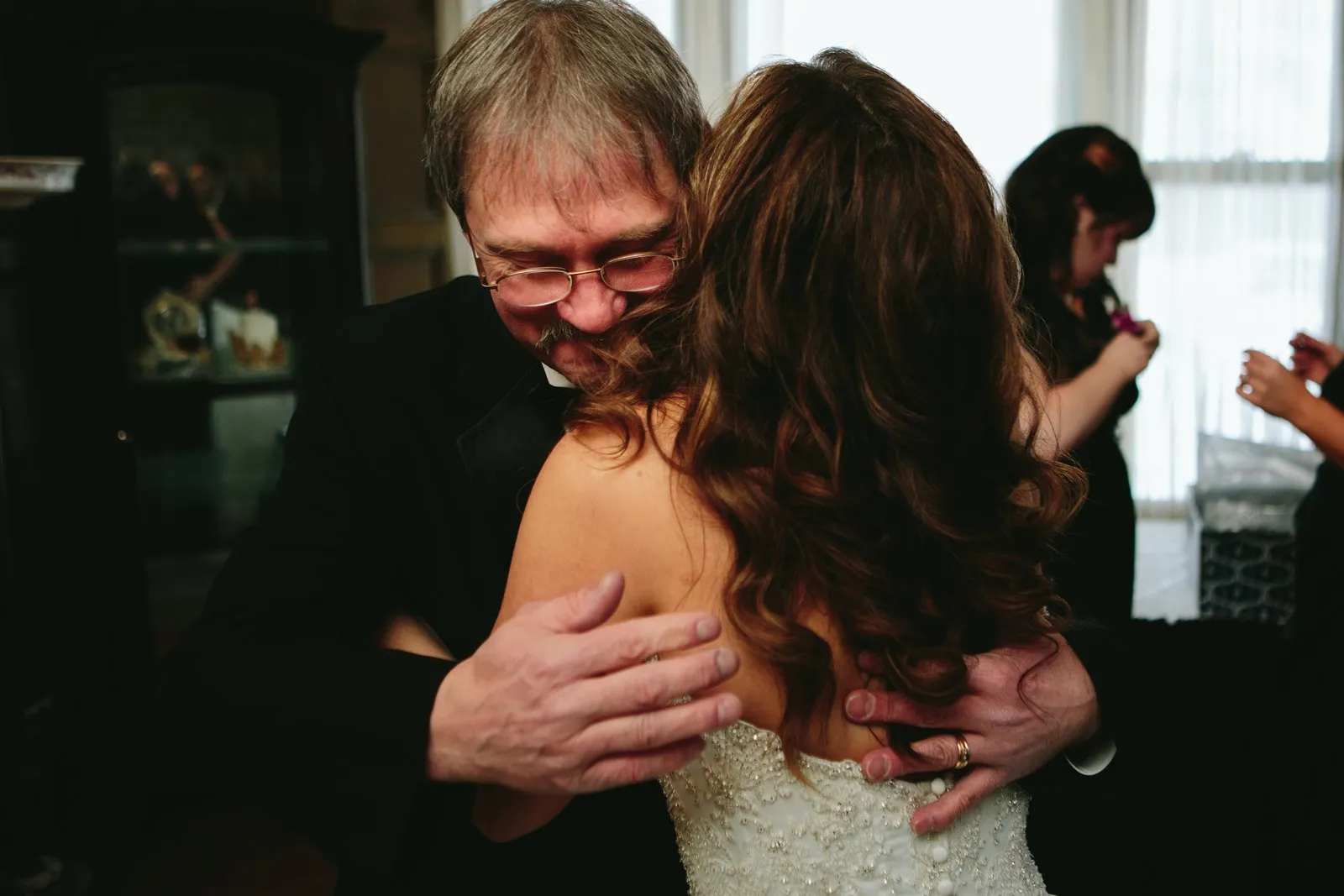 Father embracing the bride, eyes closed and hands clasping her back with wedding ring visible — tender pre-ceremony moment — Tim Larsen Photography, Duluth MN