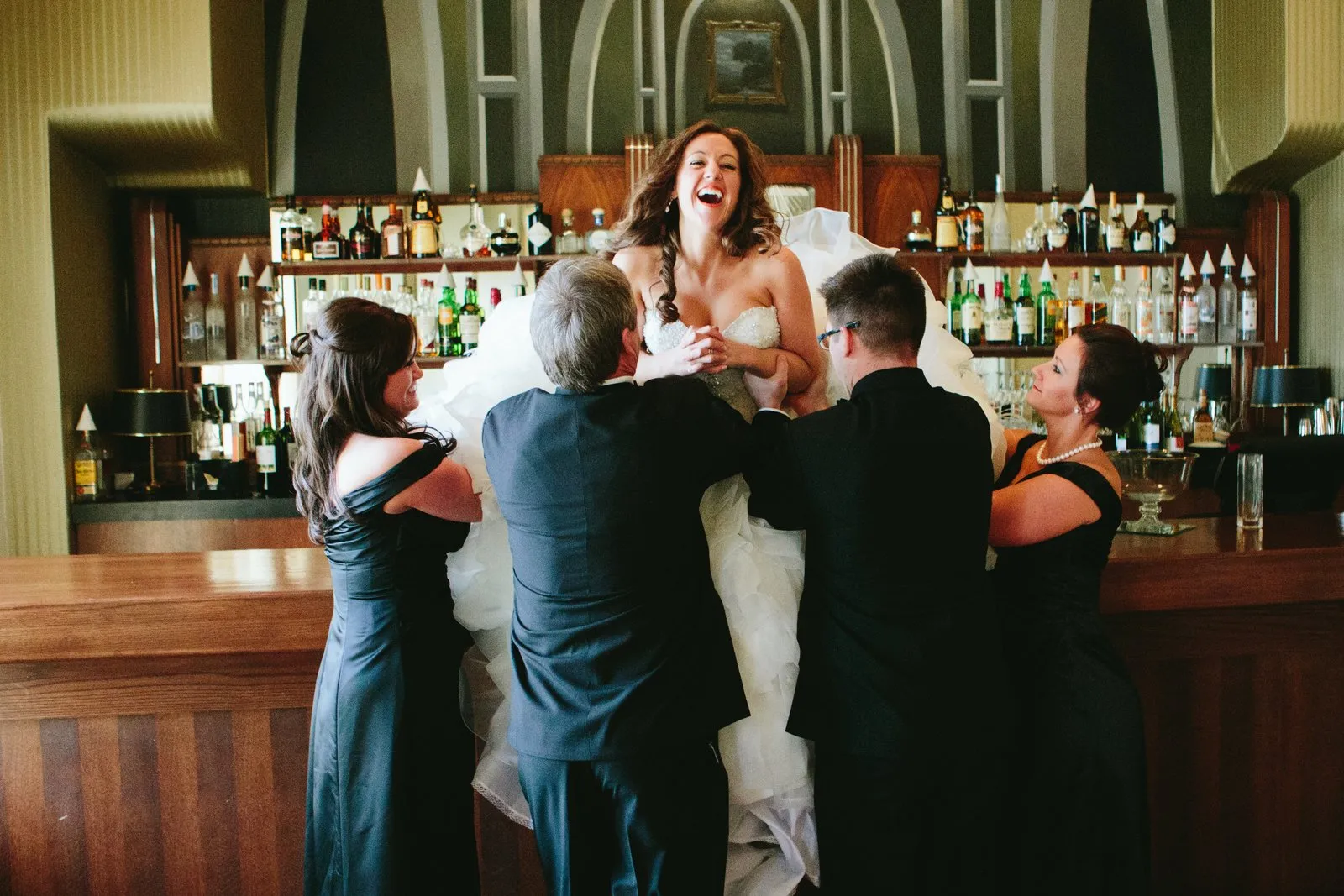 Family lifting the bride onto the historic Greysolon bar — she throws her head back laughing — Tim Larsen Photography, Duluth MN