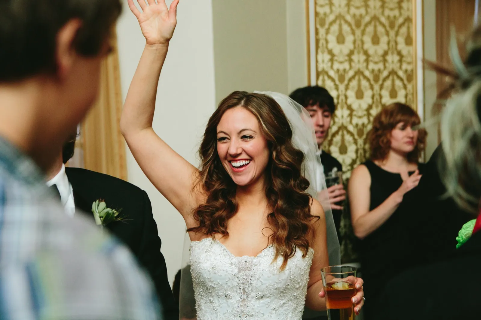 Bride mid-laugh with arm raised during cocktail hour, glass in hand — Greysolon Plaza — Tim Larsen Photography, Duluth MN