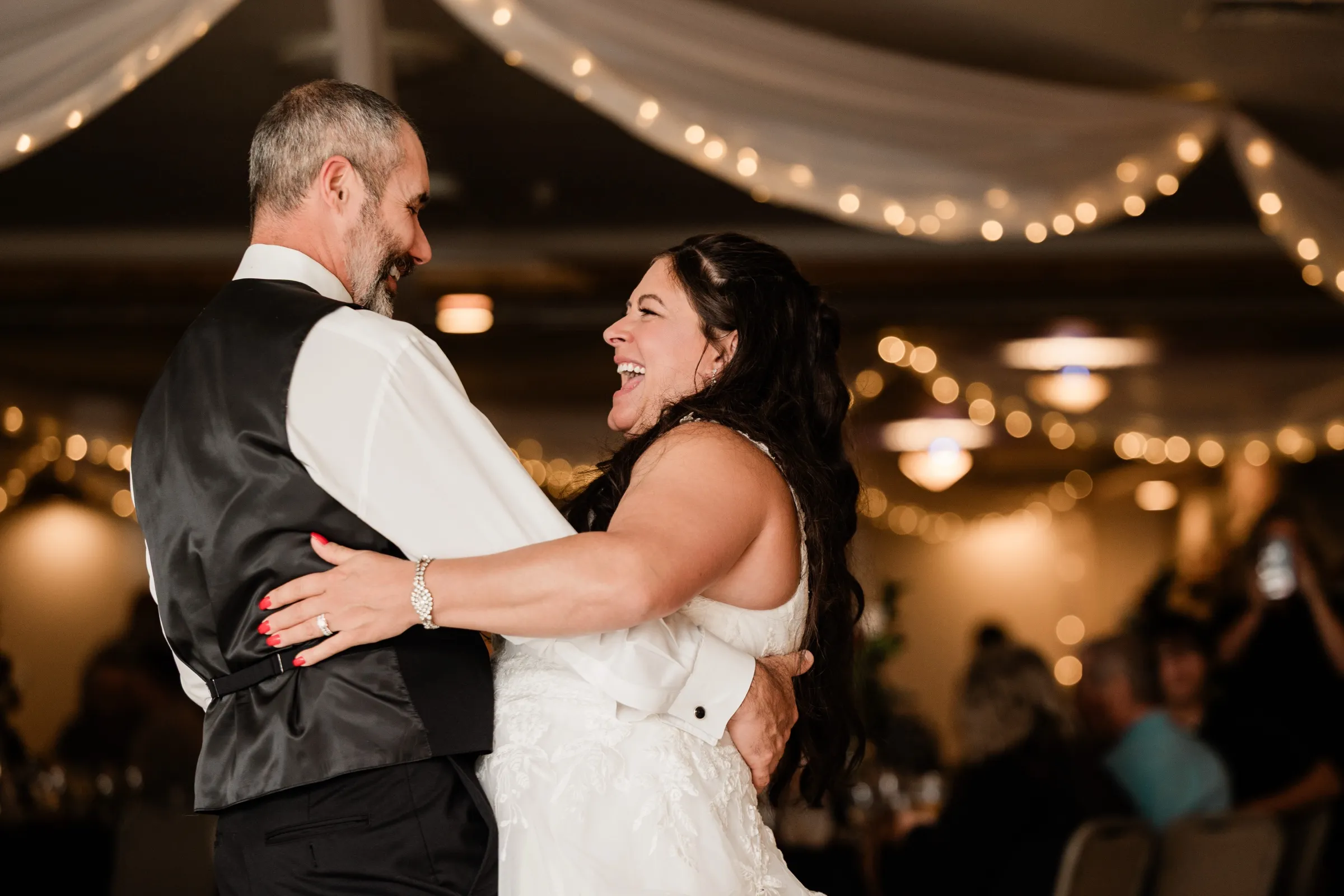 Amber laughs with her mouth open as she dances with Don under draped fabric and string lights in the ballroom. — Tim Larsen Photography, Brainerd Lakes MN