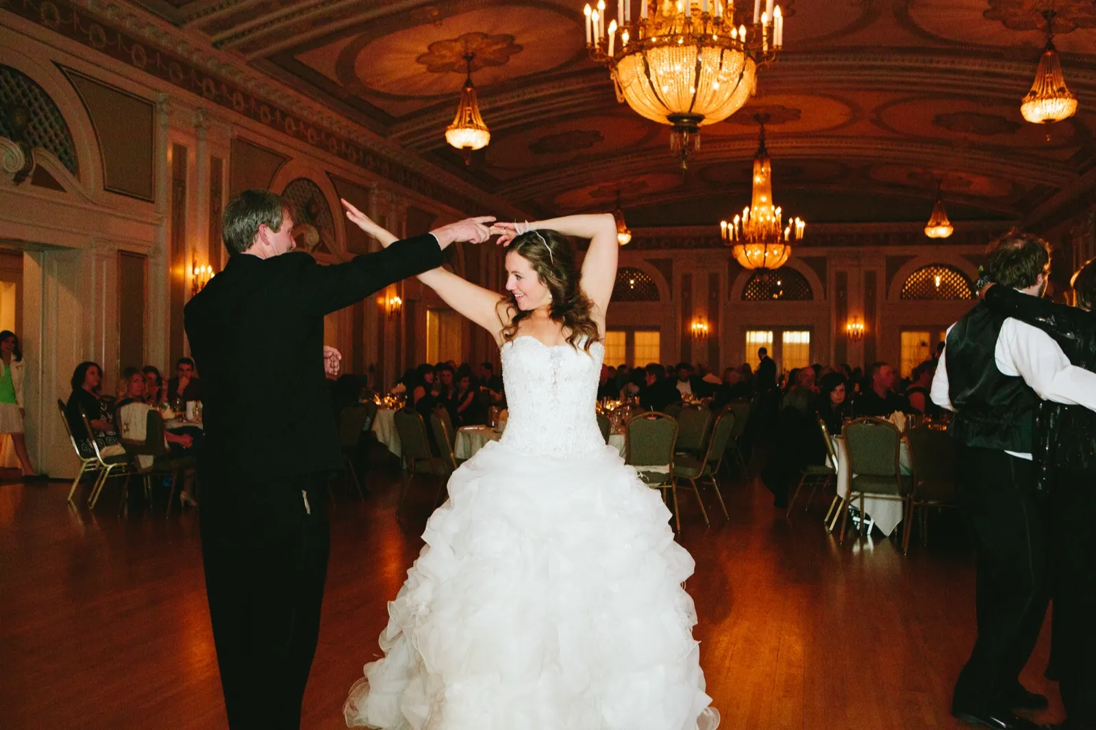 Bride mid-twirl beneath the Greysolon chandeliers, her partner's arms framing her face — parent dance — Tim Larsen Photography, Duluth MN