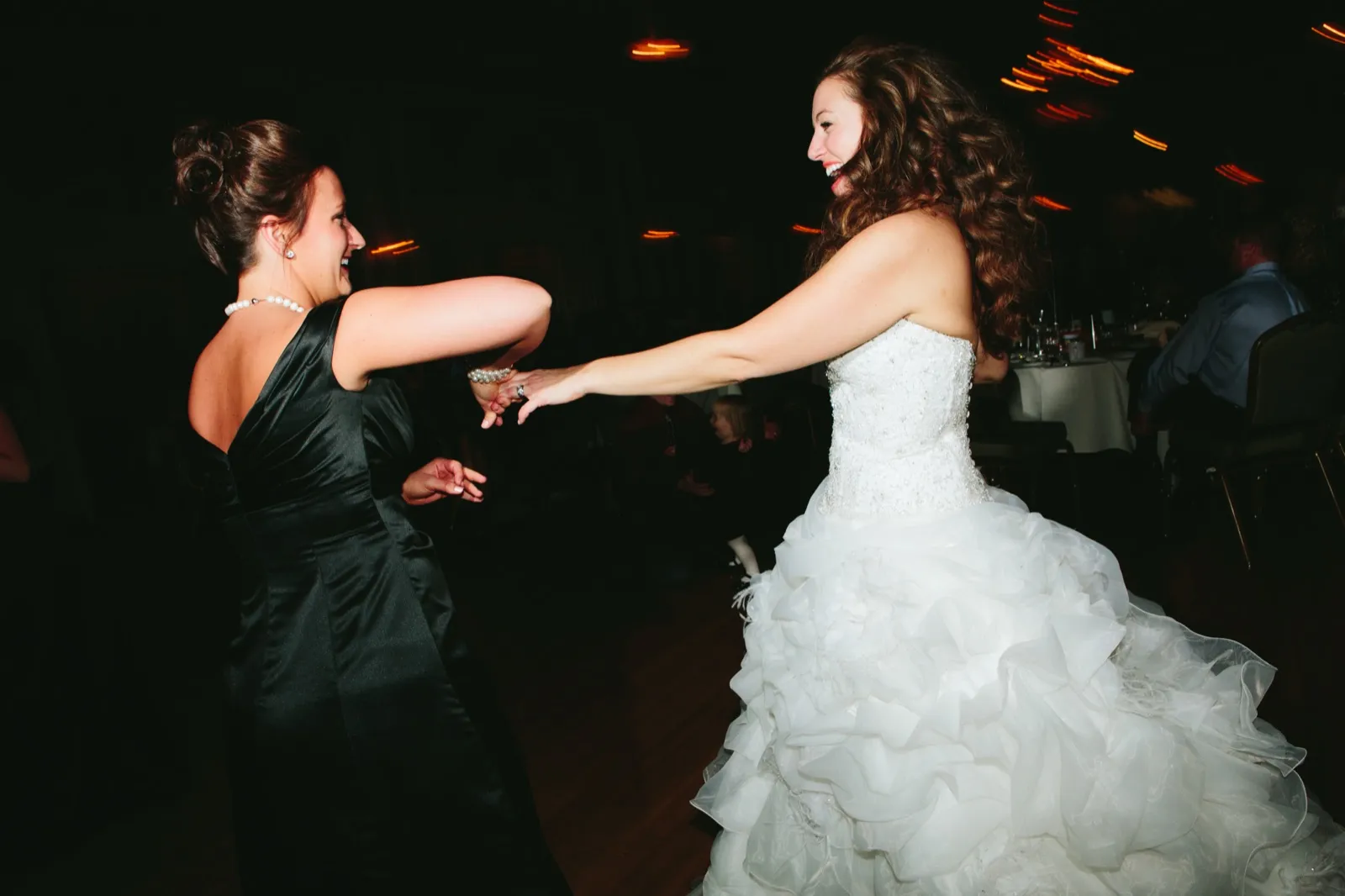 Bride mid-spin with a guest, arms extended and motion-blurred tungsten lights streaking behind — Greysolon Ballroom dance floor — Tim Larsen Photography, Duluth MN