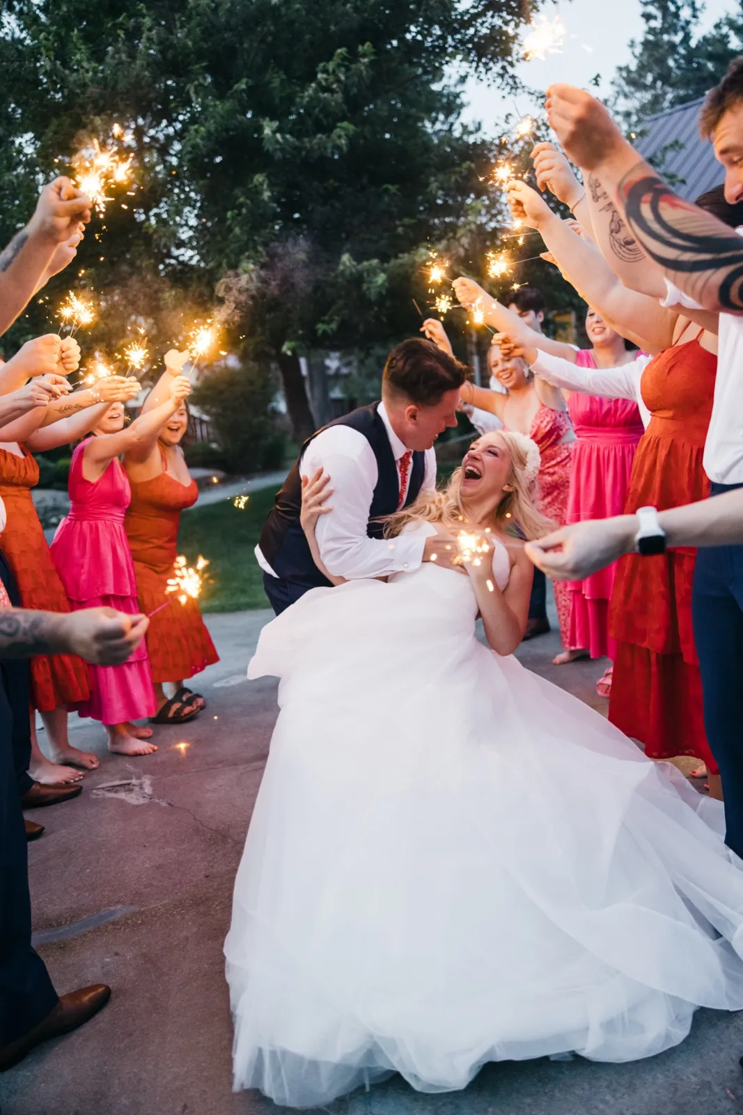 The groom dips the laughing bride at the center of a sparkler tunnel formed by their bridal party at dusk. — Tim Larsen Photography, Brainerd Lakes MN