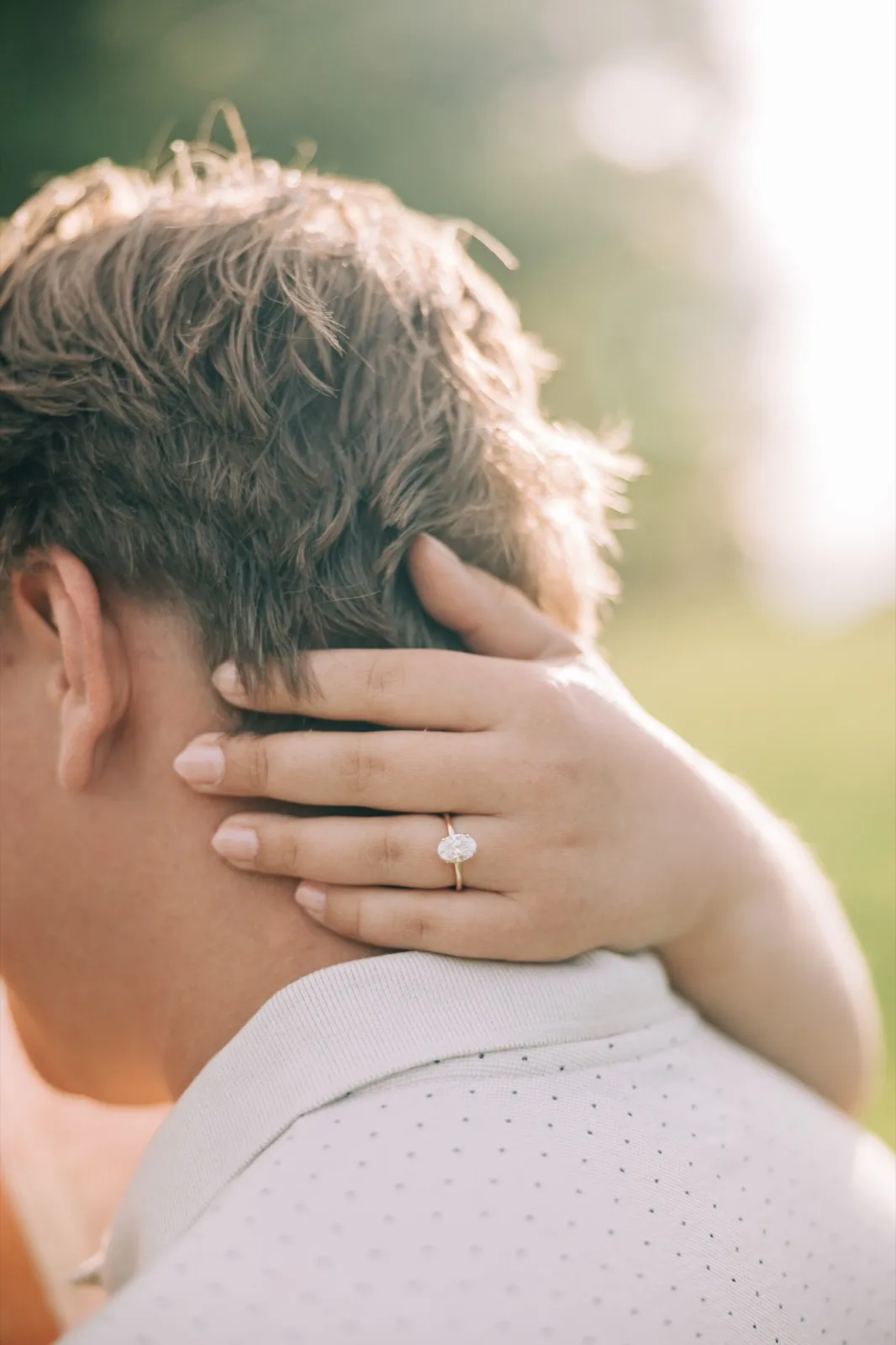 Close-up of Abby's hand on the back of Anthony's neck, her oval solitaire engagement ring in focus — Tim Larsen Photography