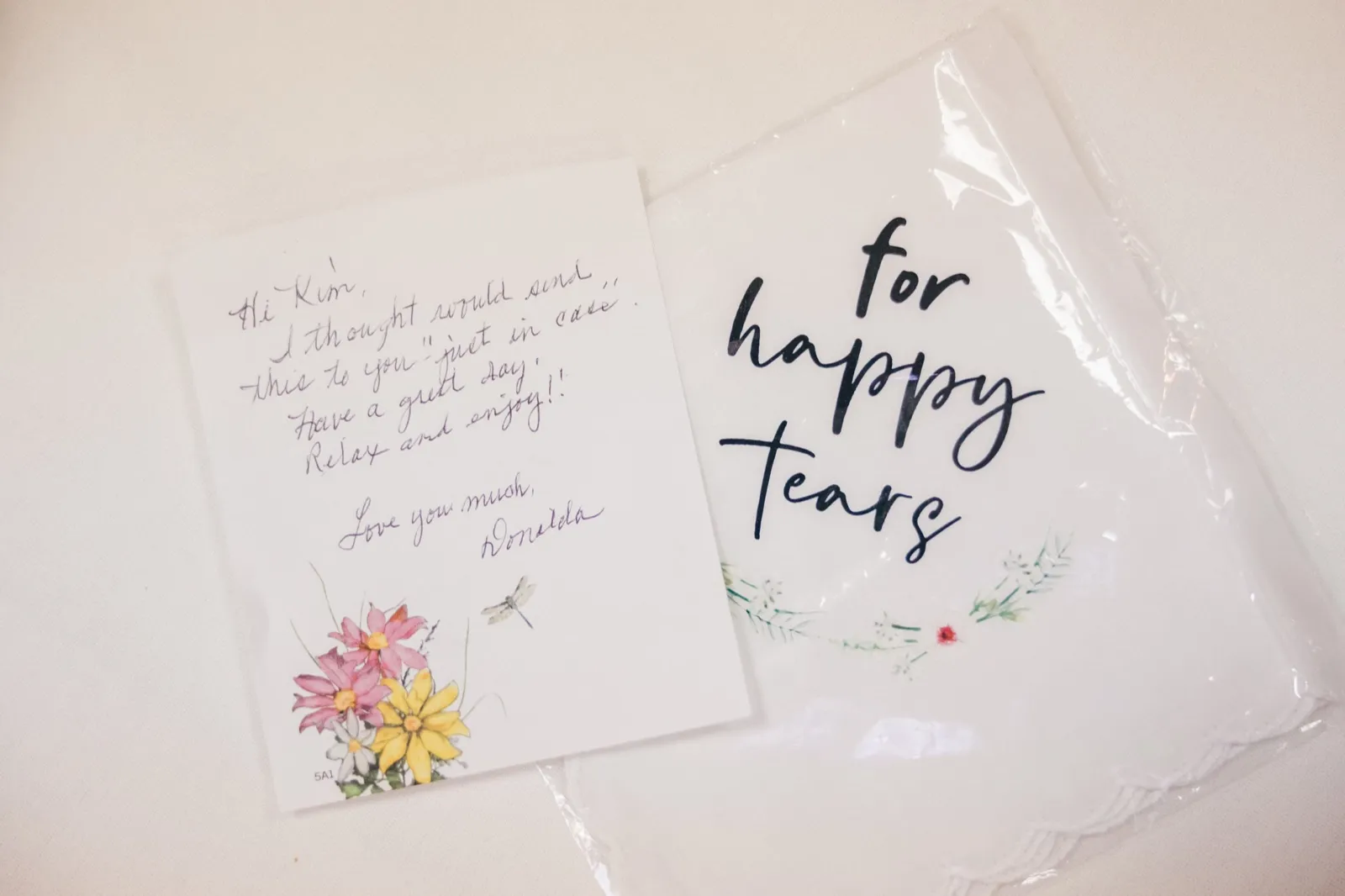 A handwritten note from Kim's mother sits beside a 'for happy tears' embroidered handkerchief on a white surface — Tim Larsen Photography, Brainerd Lakes MN