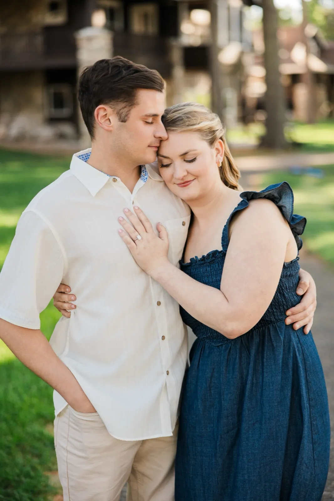 A couple rest their foreheads together with eyes closed, the woman's ring hand on her fiance's chest, on Grand View Lodge's Roy Lake grounds — Tim Larsen Photography