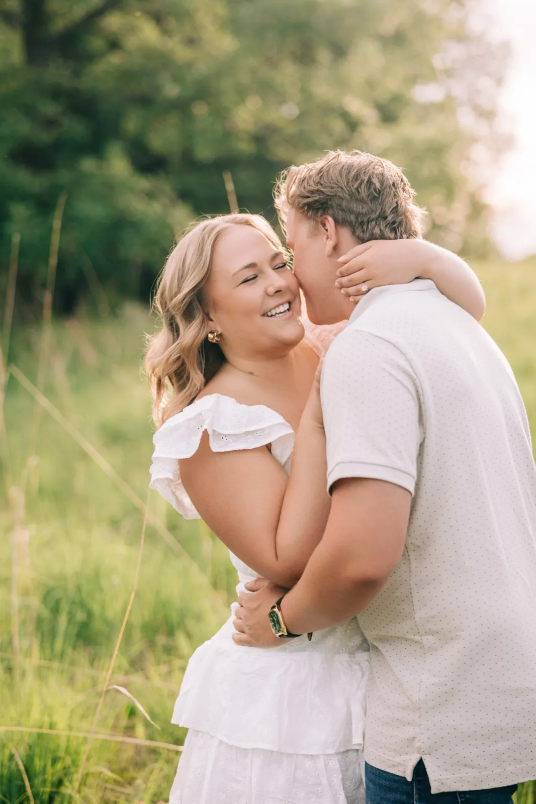 Abby laughs cheek to cheek with Anthony in the tall grass, backlit by the low evening sun — Tim Larsen Photography