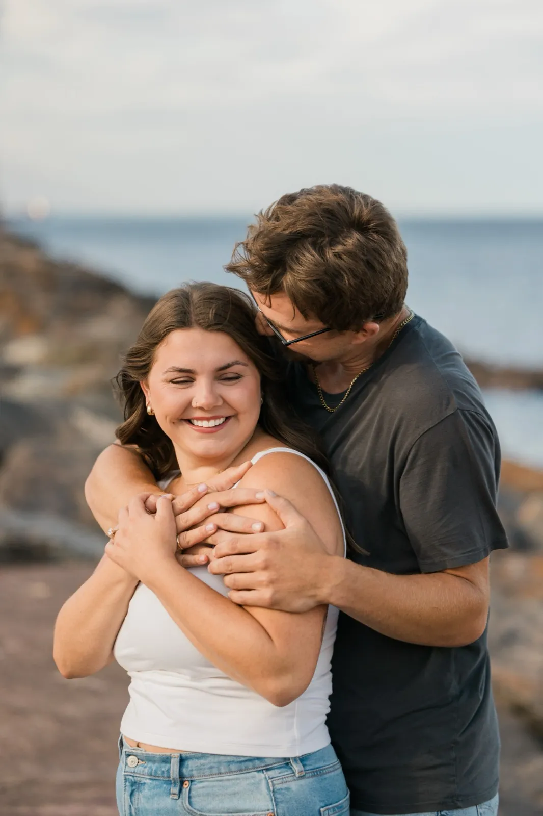 Jacklyn laughs with her eyes closed as Reeden leans into the side of her head on the Wisconsin Point breakwater — Tim Larsen Photography