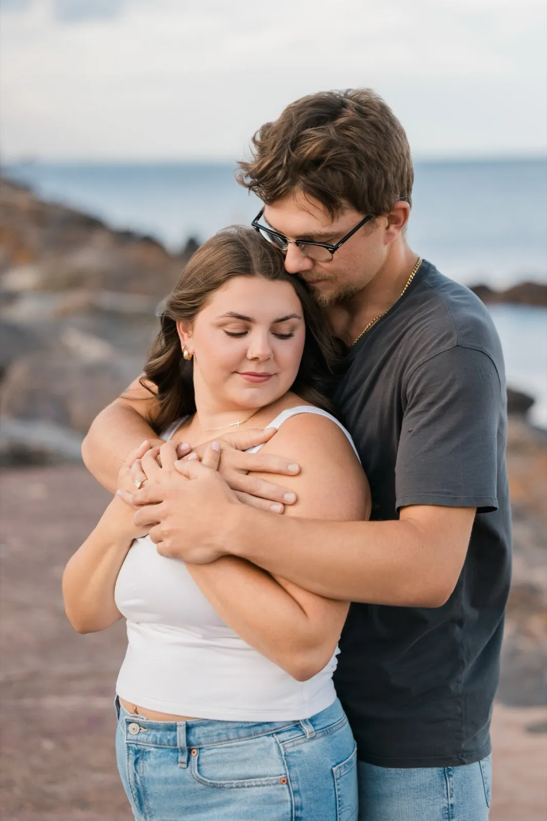 Reeden and Jacklyn stand wrapped together with their eyes closed, hands clasped at her chest and her engagement ring showing — Tim Larsen Photography