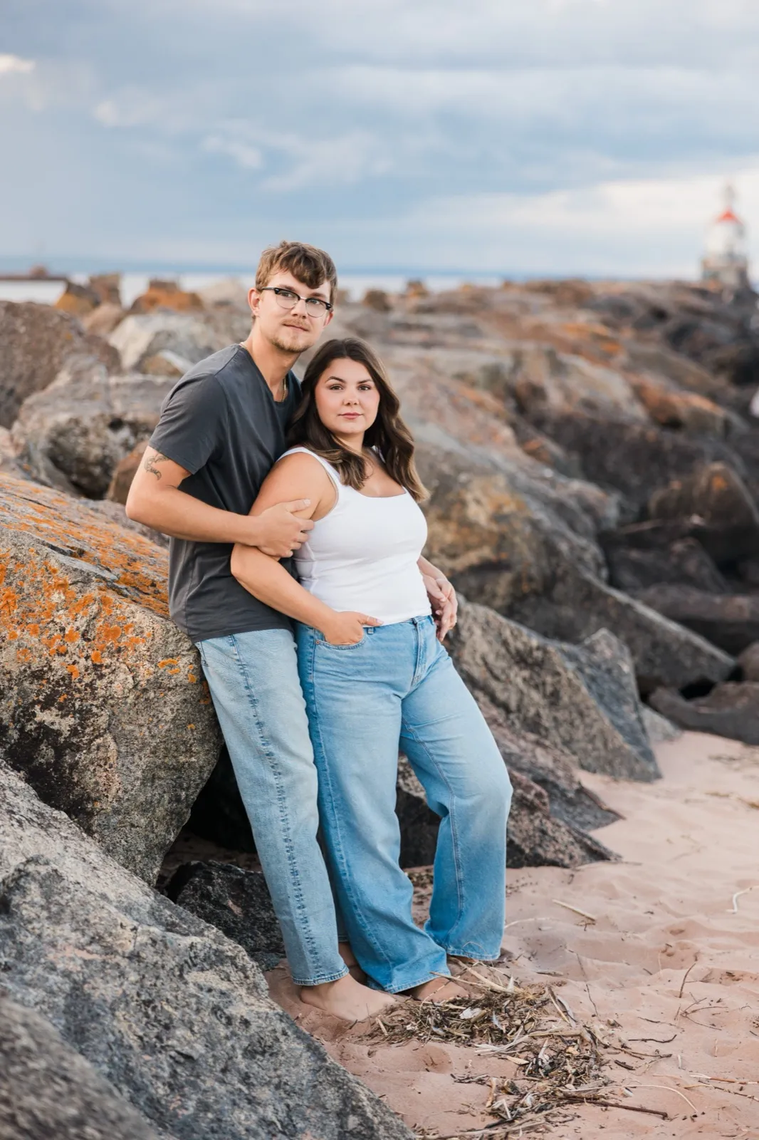 Reeden and Jacklyn lean against the big lichen-covered boulders on the Lake Superior beach, looking straight at the camera — Tim Larsen Photography
