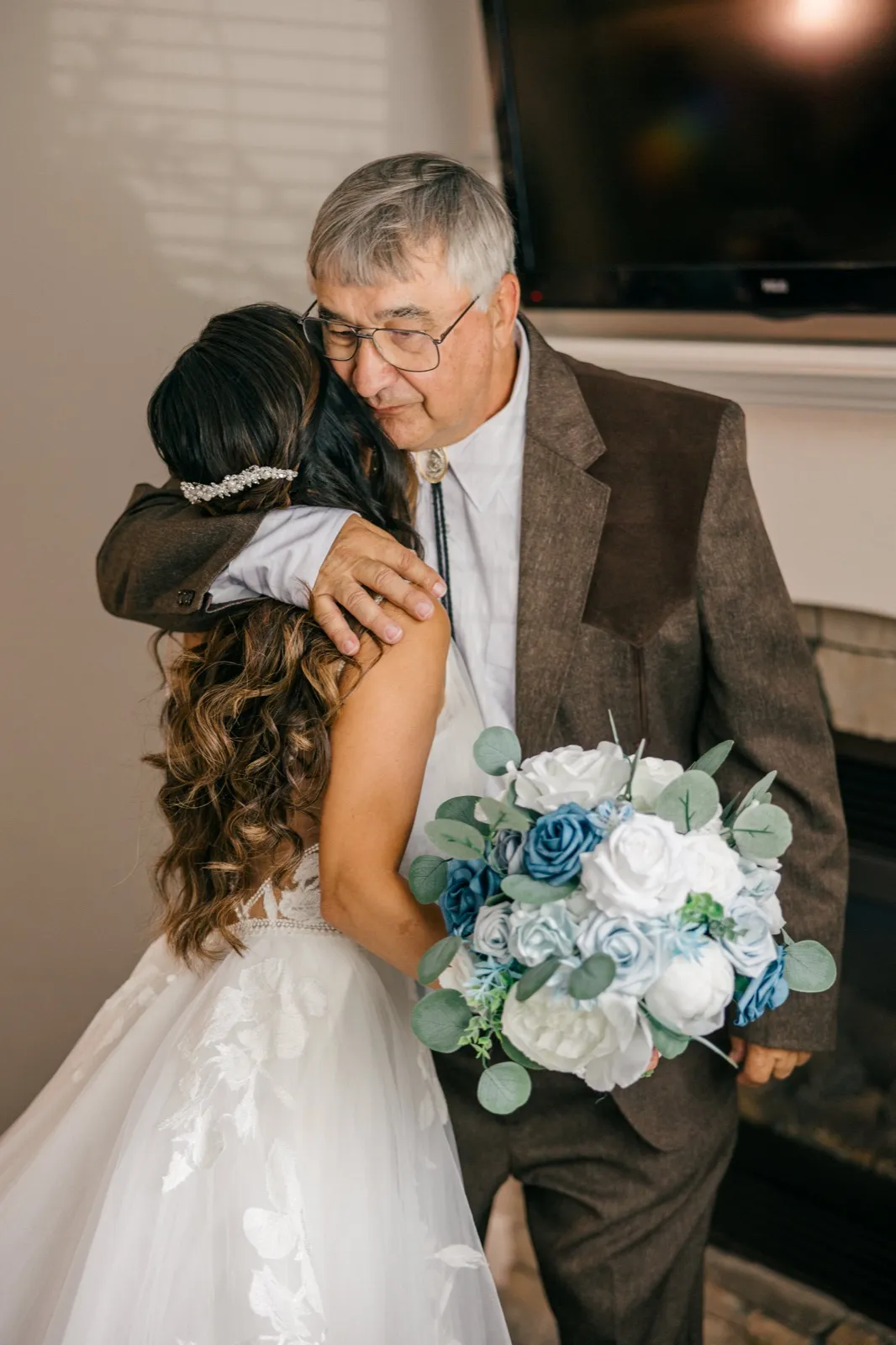 The bride embraces her father, whose eyes close with emotion as he holds her shoulder, her dusty-blue and white bouquet visible at her side — Tim Larsen Photography, Brainerd Lakes MN