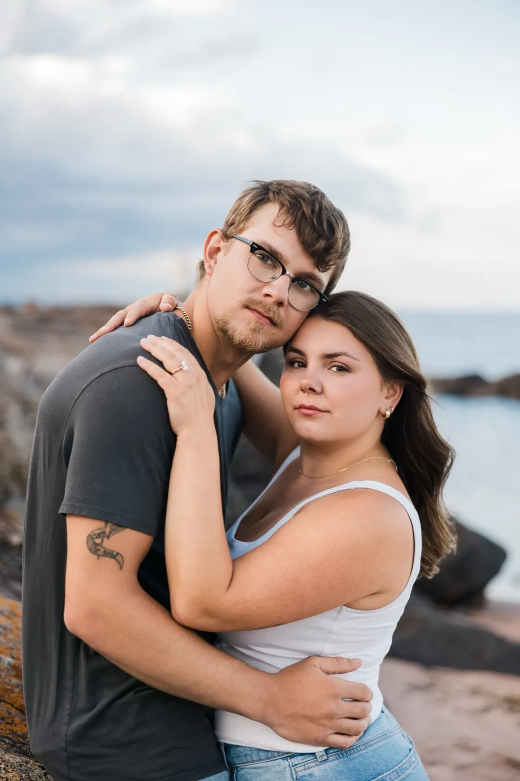 Reeden and Jacklyn rest their heads together and look calmly into the camera, Lake Superior soft behind them — Tim Larsen Photography