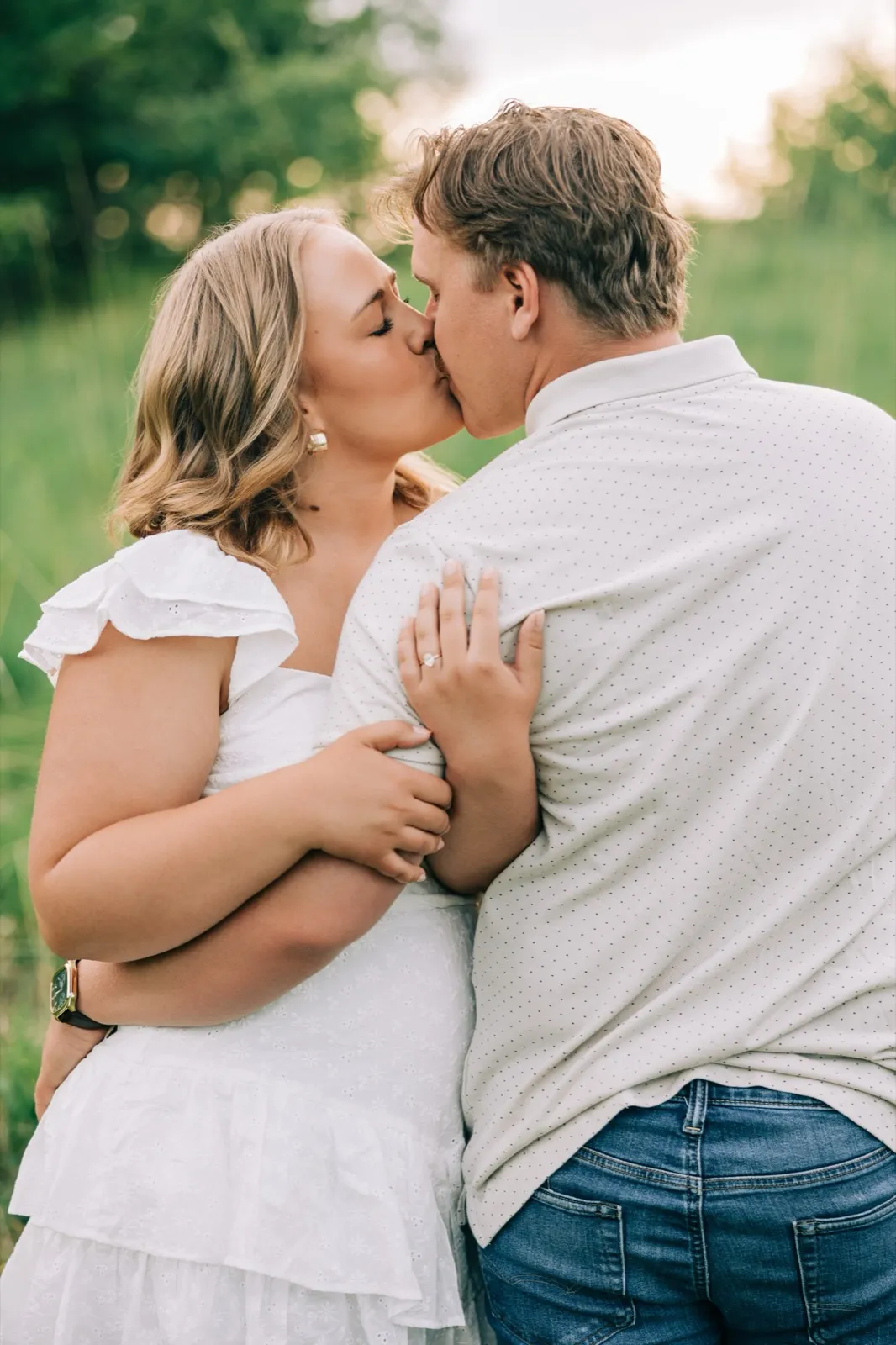 Abby and Anthony kiss in the tall grass, her hand and engagement ring against his chest — Tim Larsen Photography