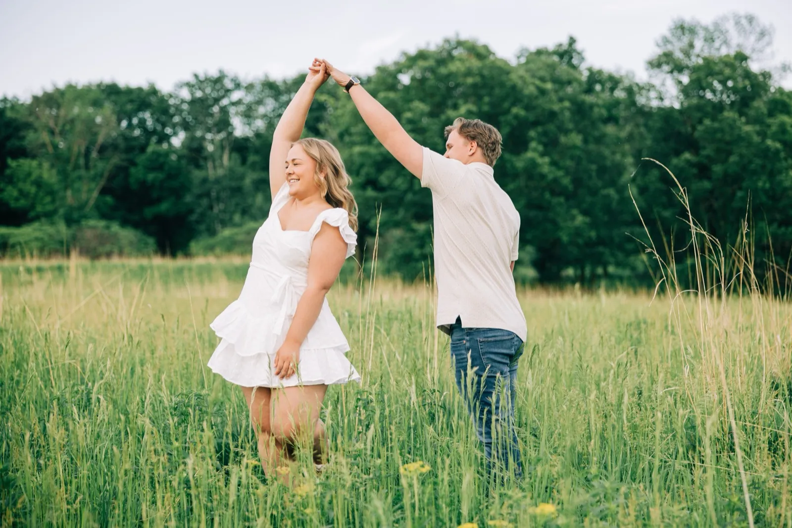 Anthony spins Abby by the hand through the tall grass, her dress swinging in the golden light — Tim Larsen Photography