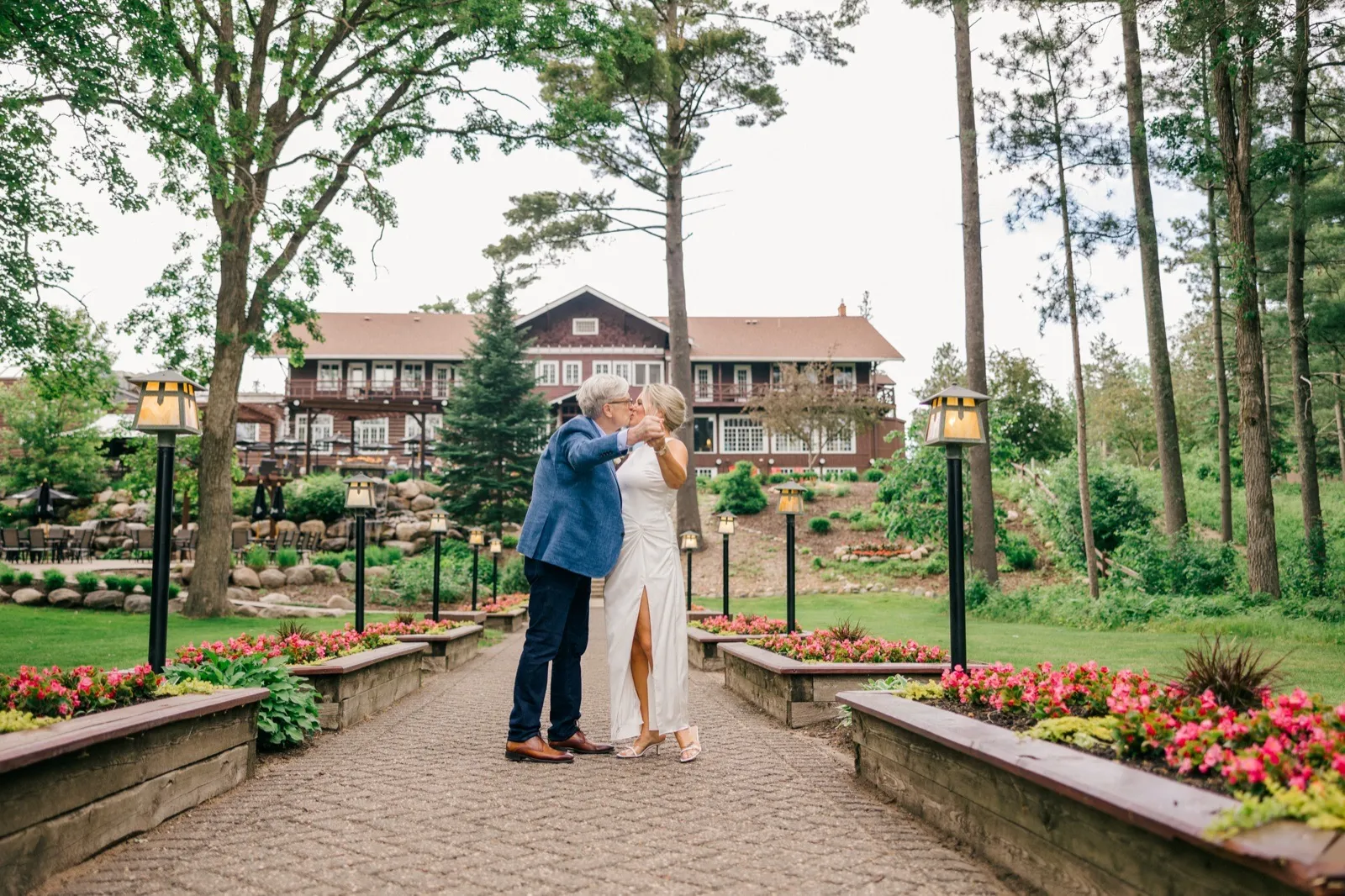 The couple kisses on a lantern-lined garden pathway with the historic Grand View Lodge main building behind them — Tim Larsen Photography, Brainerd Lakes MN