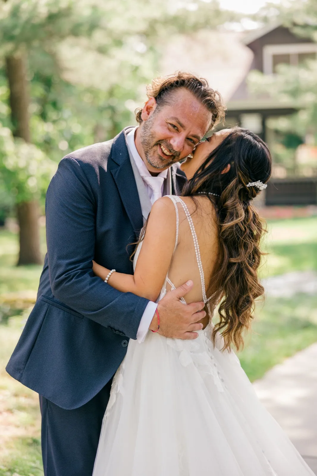 The bride nuzzles into the groom's cheek as he breaks into a wide grin during a portrait on the Grand View Lodge grounds — Tim Larsen Photography, Brainerd Lakes MN
