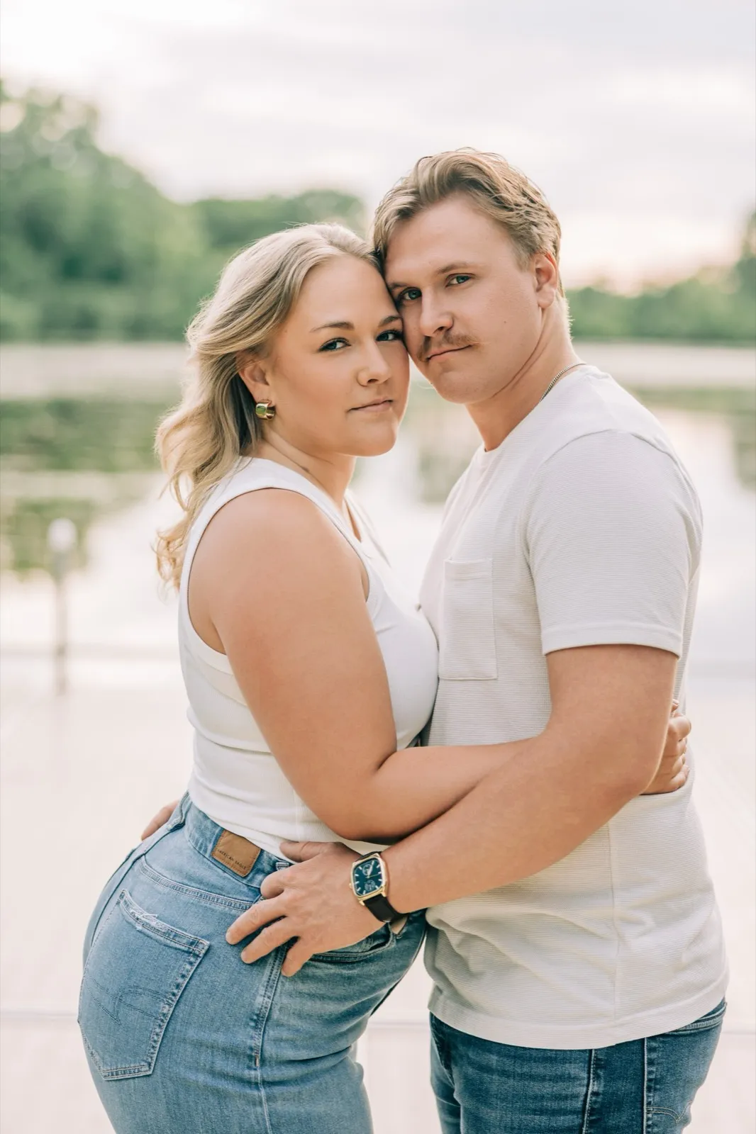Abby and Anthony lean cheek to cheek and look at the camera on the Lake Auburn dock — Tim Larsen Photography