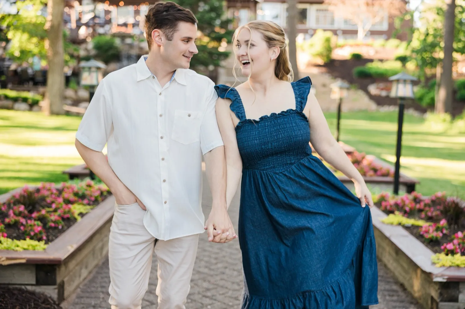 An engaged couple walk toward the camera holding hands on the Grand View Lodge garden staircase, the woman laughing and swishing her skirt — Tim Larsen Photography