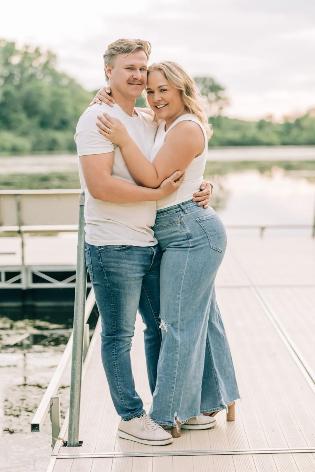 Abby looks back over her shoulder with a smile, her hand and engagement ring resting on Anthony's back by Lake Auburn — Tim Larsen Photography